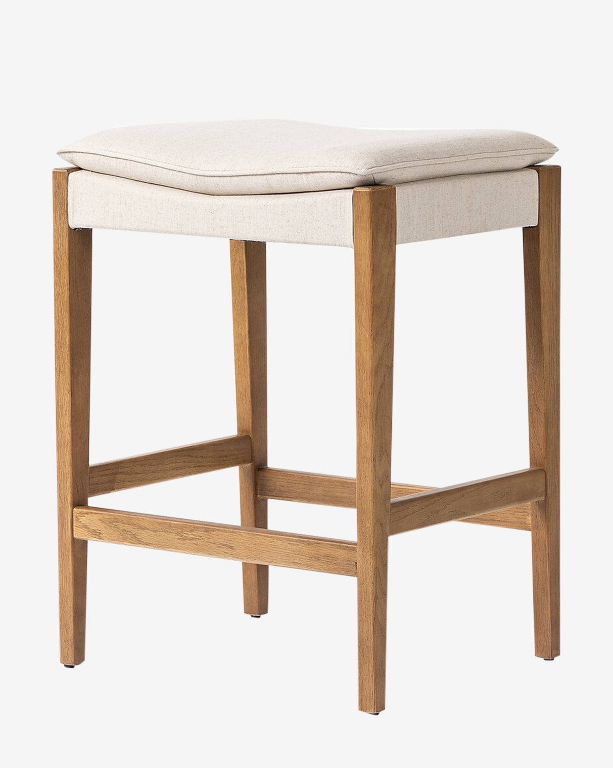 The Kaelith Counter Stool by Four Hands features a solid oak frame, light beige cushioned seat, and four straight legs with support bars. Its simple modern design and light wood finish suit any kitchen countertop. McGee & Co.