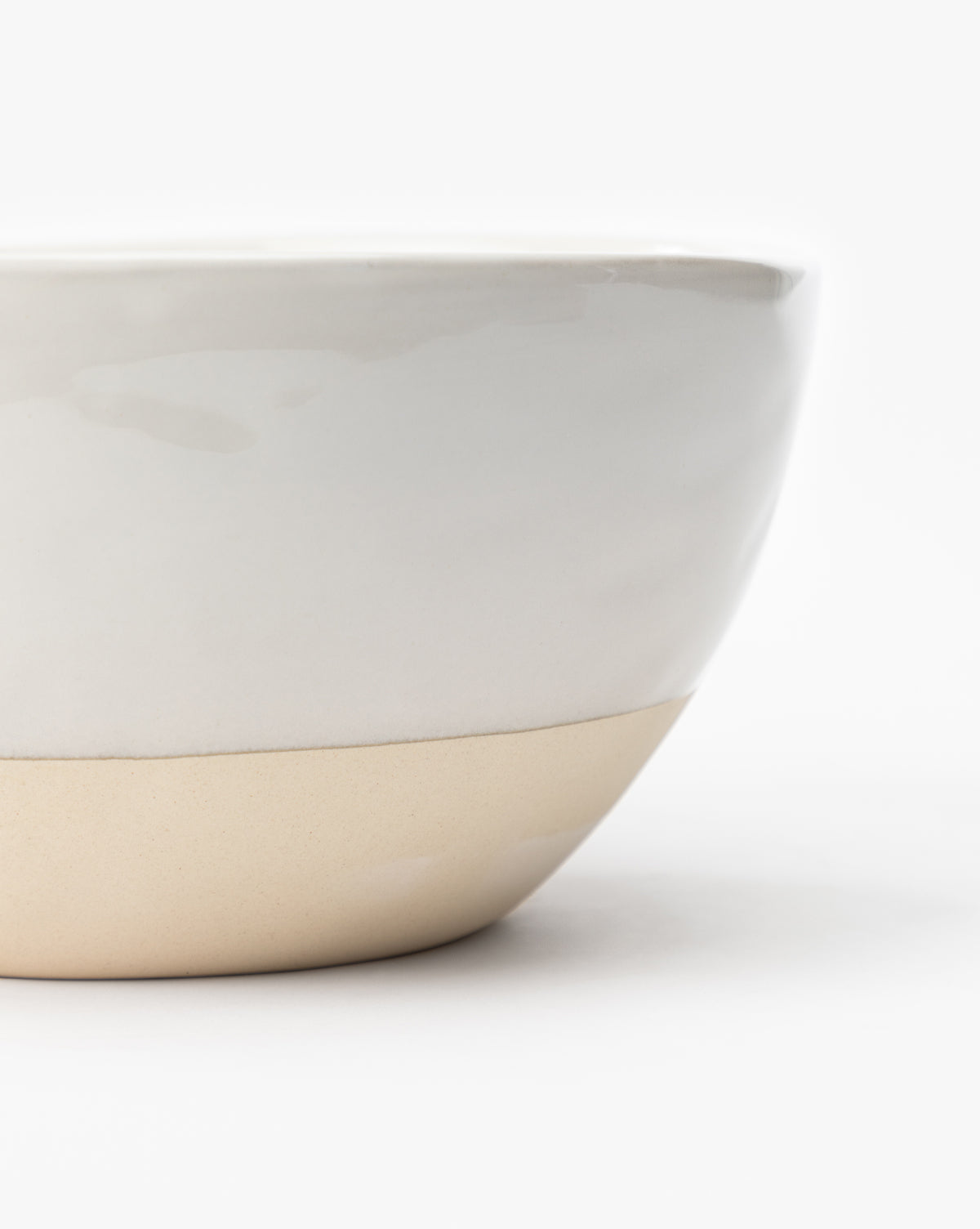 A close-up of the Karina Stoneware Batter Bowls (Set of 4), featuring a white glossy upper half and unglazed beige lower half, set against a plain background, evokes vintage baking charm, by McGee & Co.