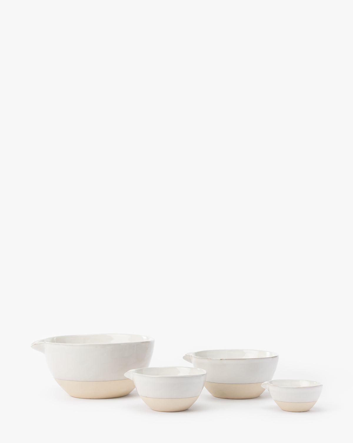 The Karina Stoneware Batter Bowls (Set of 4) are shown in a row on a white background. Each white bowl features a subtle beige base, and the largest bowl on the left has a spout, evoking classic vintage baking charm, by McGee & Co.