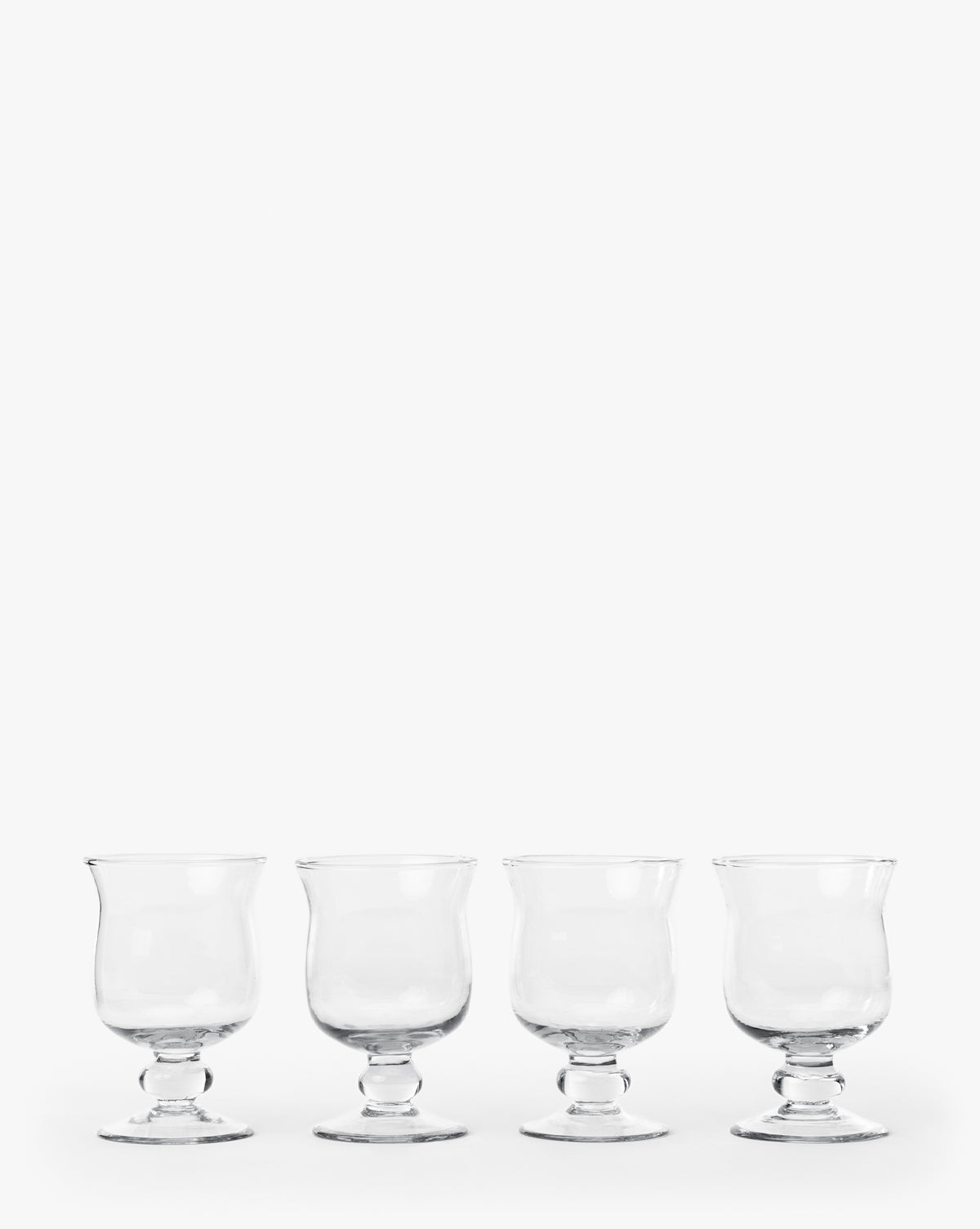 The Keely Goblets (Set of 4) are clear recycled glass goblets with short stems, evenly spaced in a row against a white background—ideal for modern dining, by McGee & Co.