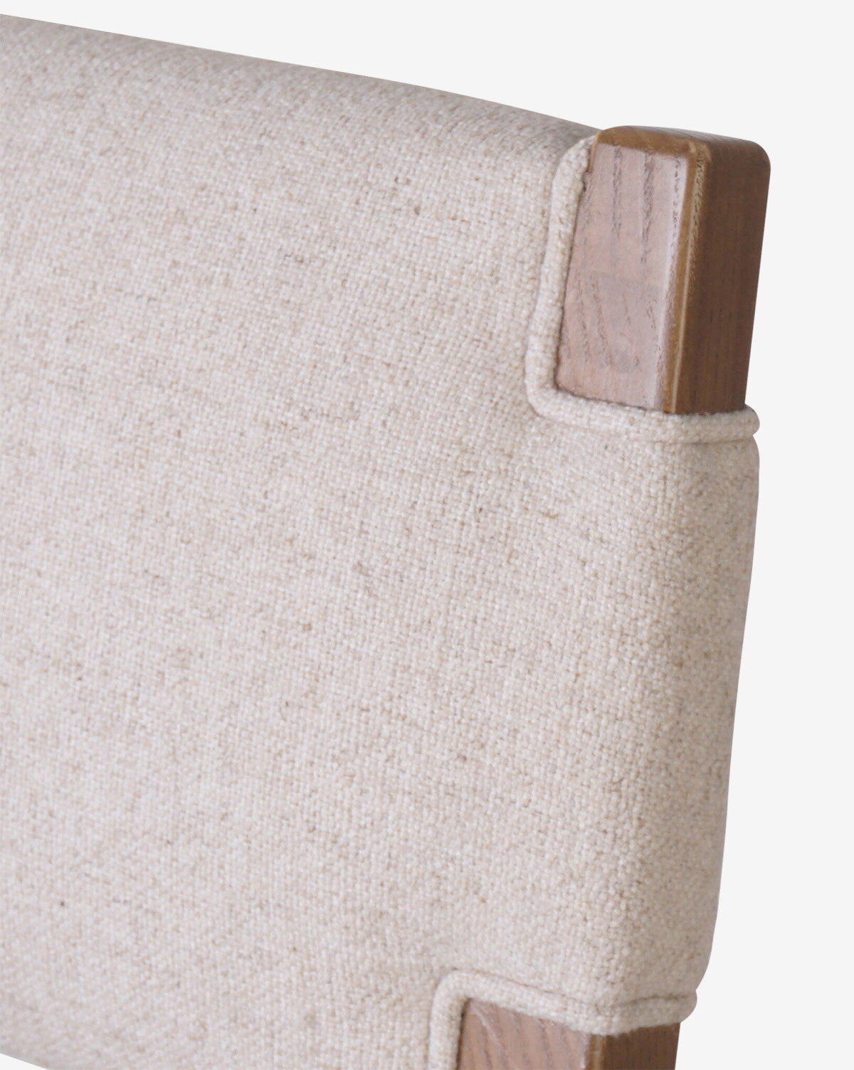 Close-up of the Kennebec Stool by Four Hands, featuring a beige performance fabric backrest and a visible ash wood frame at the corners. McGee & Co.