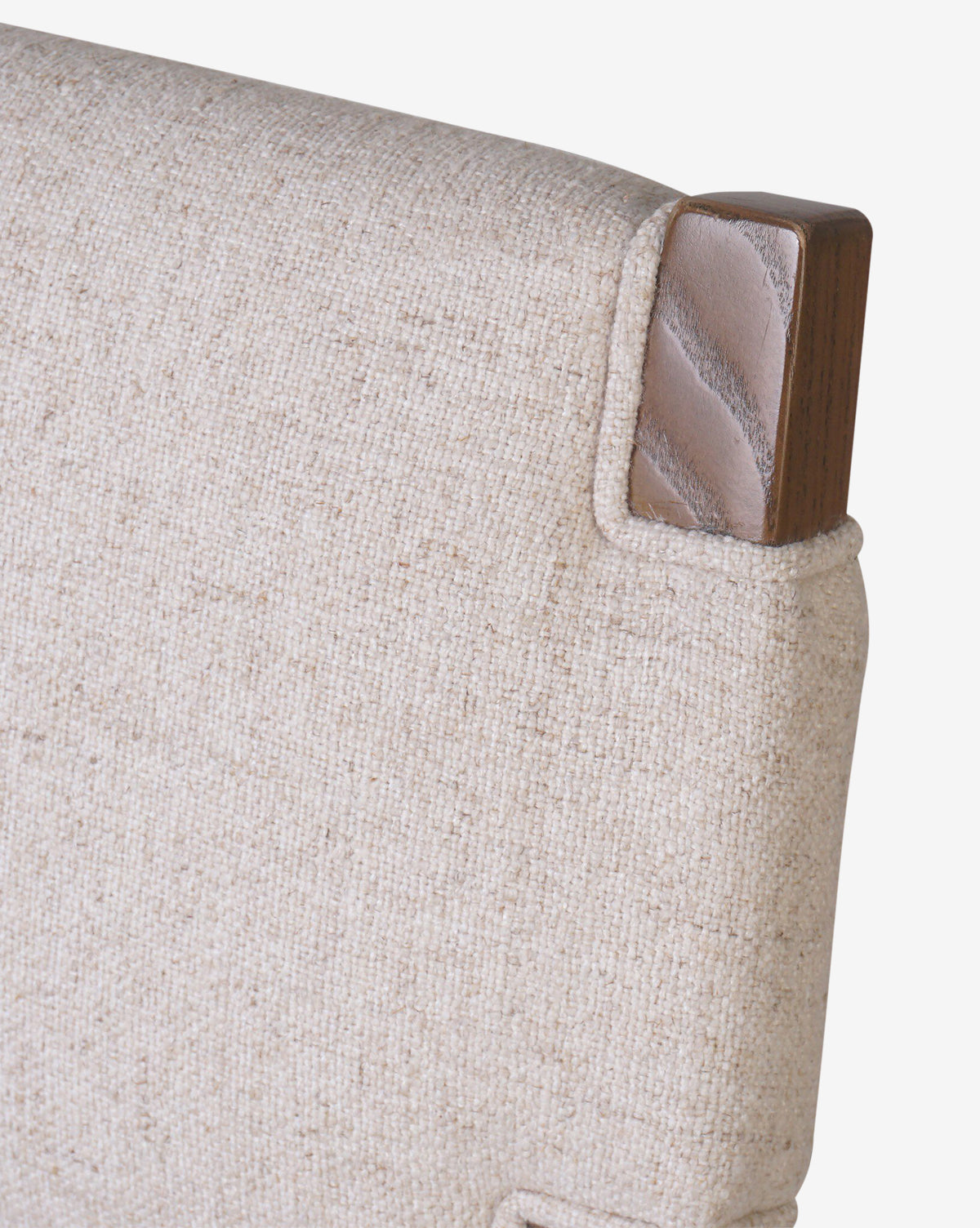 Close-up of the Kennebec Stool by Four Hands shows a beige performance fabric backrest with a wooden corner accent, highlighting the texture and rich ash grain detail. McGee & Co.