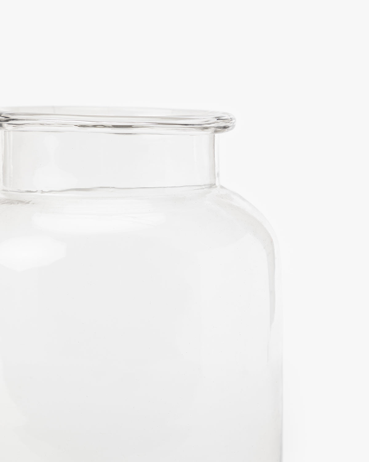 Close-up of the upper part of a Kern Glass Jar, showcasing its wide opening and smooth, transparent surface against a plain white background. Only part of this decorative glass jar is visible, emphasizing its airy style.