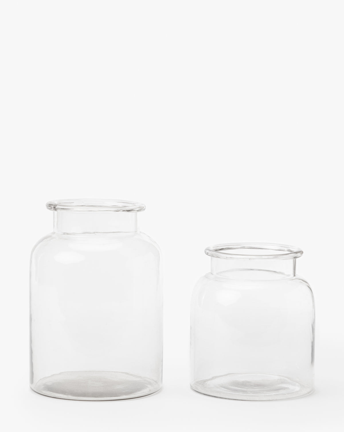 Two Kern Glass Jars are displayed side by side on a plain white background. The left jar is taller, while the shorter right jar is slightly wider, making it ideal for adding an airy decorative touch.
