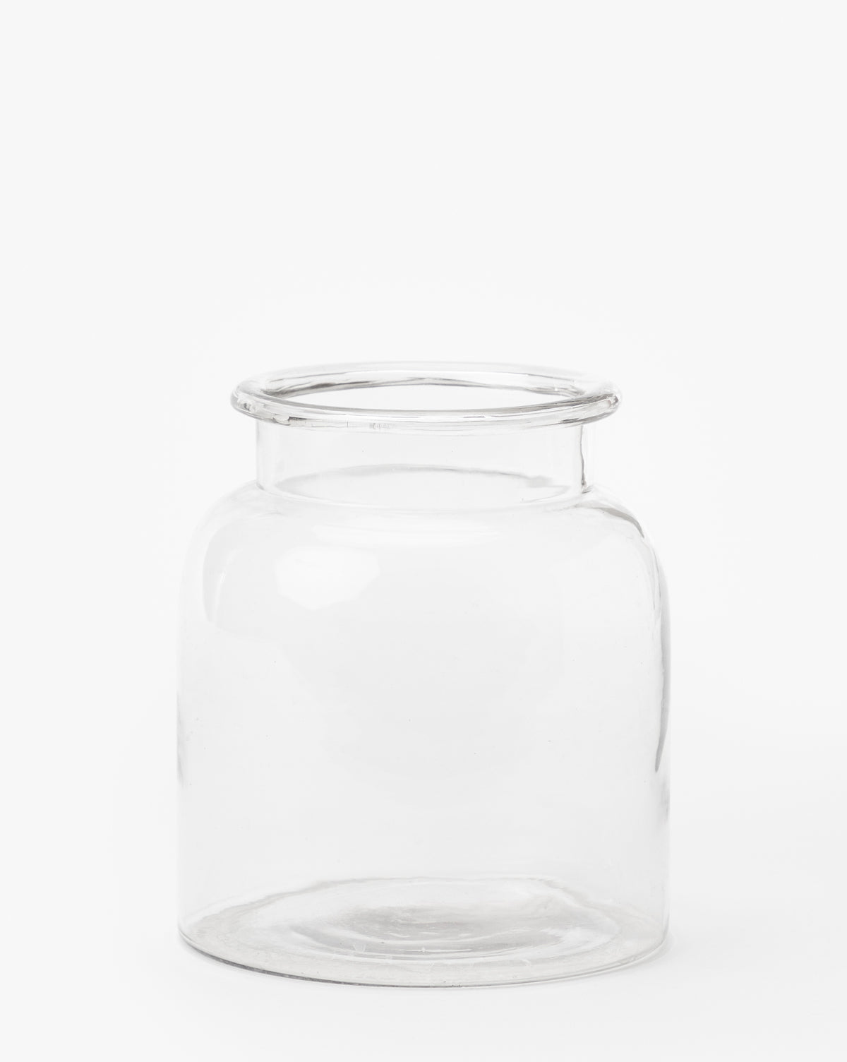 The Kern Glass Jar features a clear, wide-mouth design with a thick rim. Displayed empty against a plain white background, it highlights its simple and airy style.