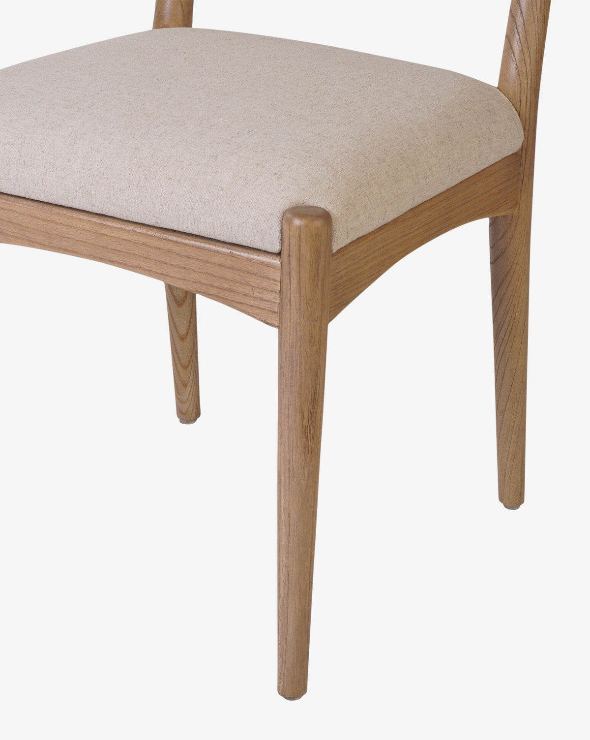 A close-up of the Kimball Dining Chair features its smooth, curved wood legs and light beige fabric seat cushion, highlighting a minimalist design set against a white background by McGee & Co.