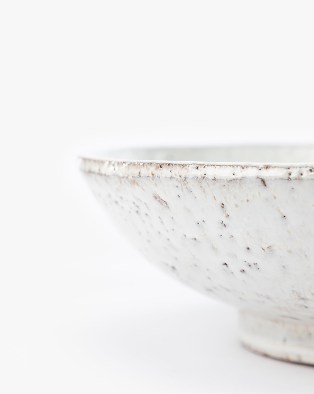 A close-up of the Kimpton Ceramic Bowl with a white speckled finish, photographed against a plain white background. The partially visible rim and textured surface highlight its decorative design, by McGee & Co.