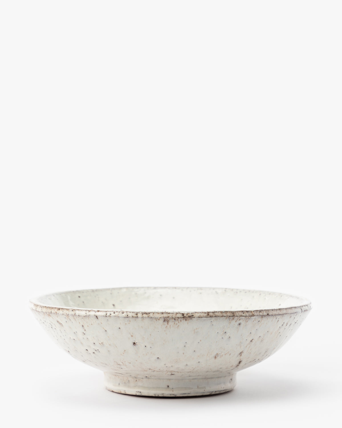 The Kimpton Ceramic Bowl is a shallow, round ceramic piece with a white speckled finish and a slightly textured, rustic look, shown against a plain white background, by McGee & Co.