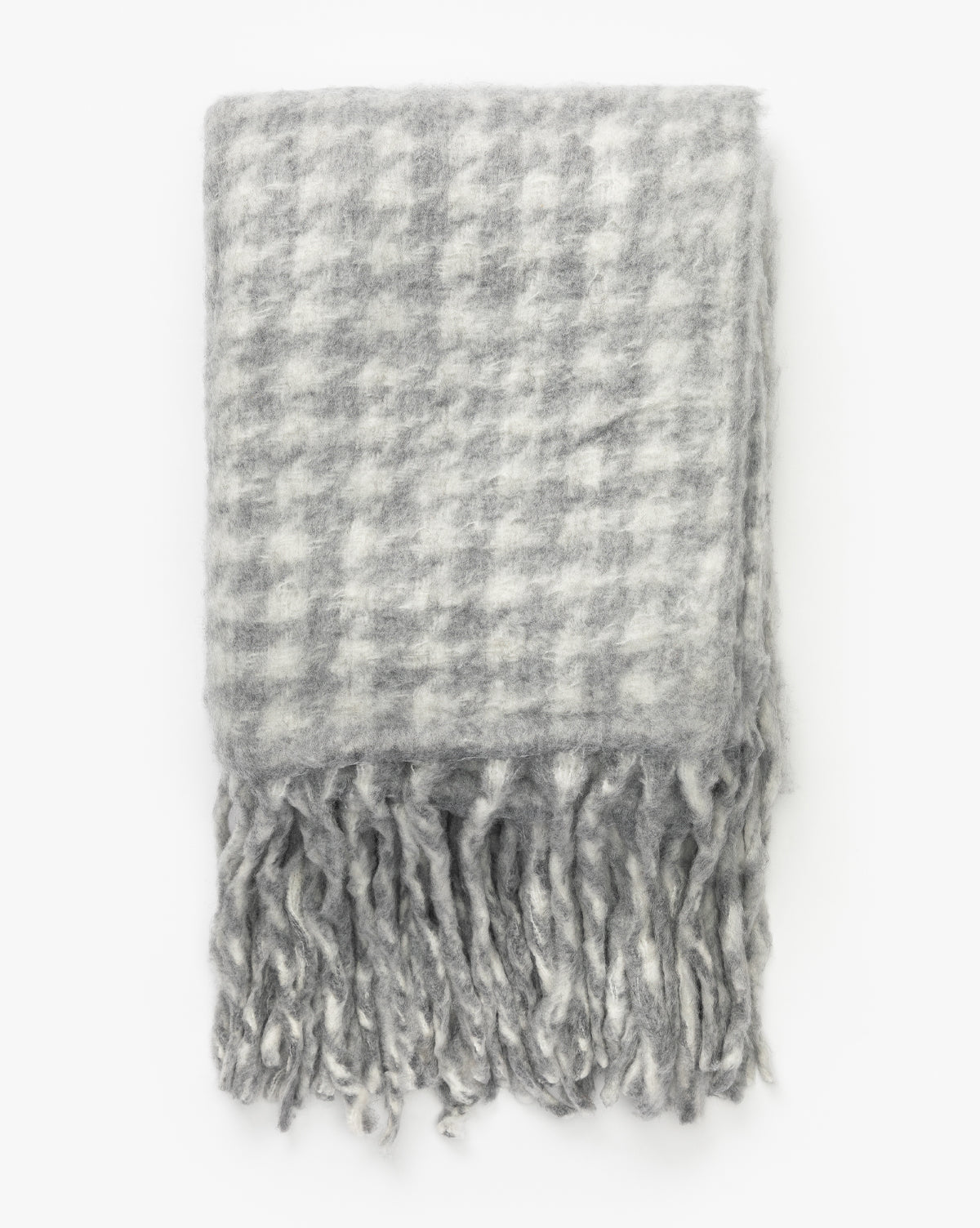 The Indaba Kirsley Houndstooth Throw is a soft wool blend with gray and white houndstooth pattern and long, thick fringes, shown folded against a white background—ideal for luxury home decor. McGee & Co.
