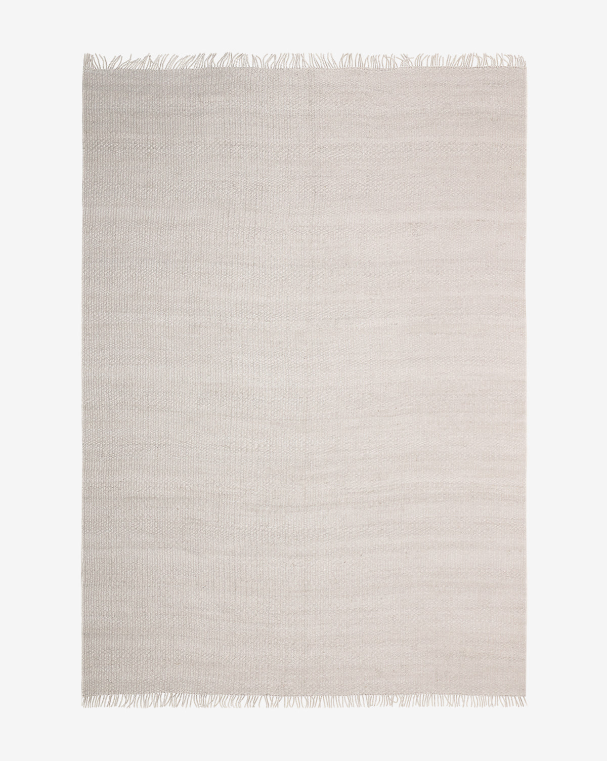 The Kit Handwoven Jute Rug is a large, rectangular piece in light beige with an organic texture and short fringe on both ends, shown against a plain white background by McGee & Co.