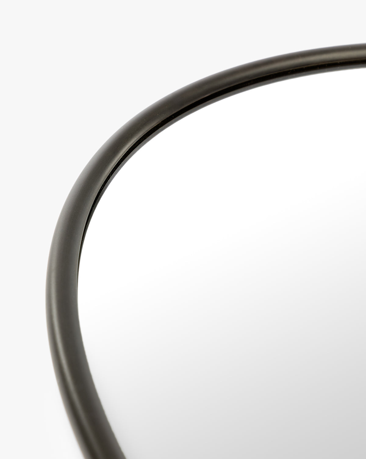 Close-up of the Kitson Oval Mirror’s thin, antique brass frame shown against a white background, by McGee & Co.