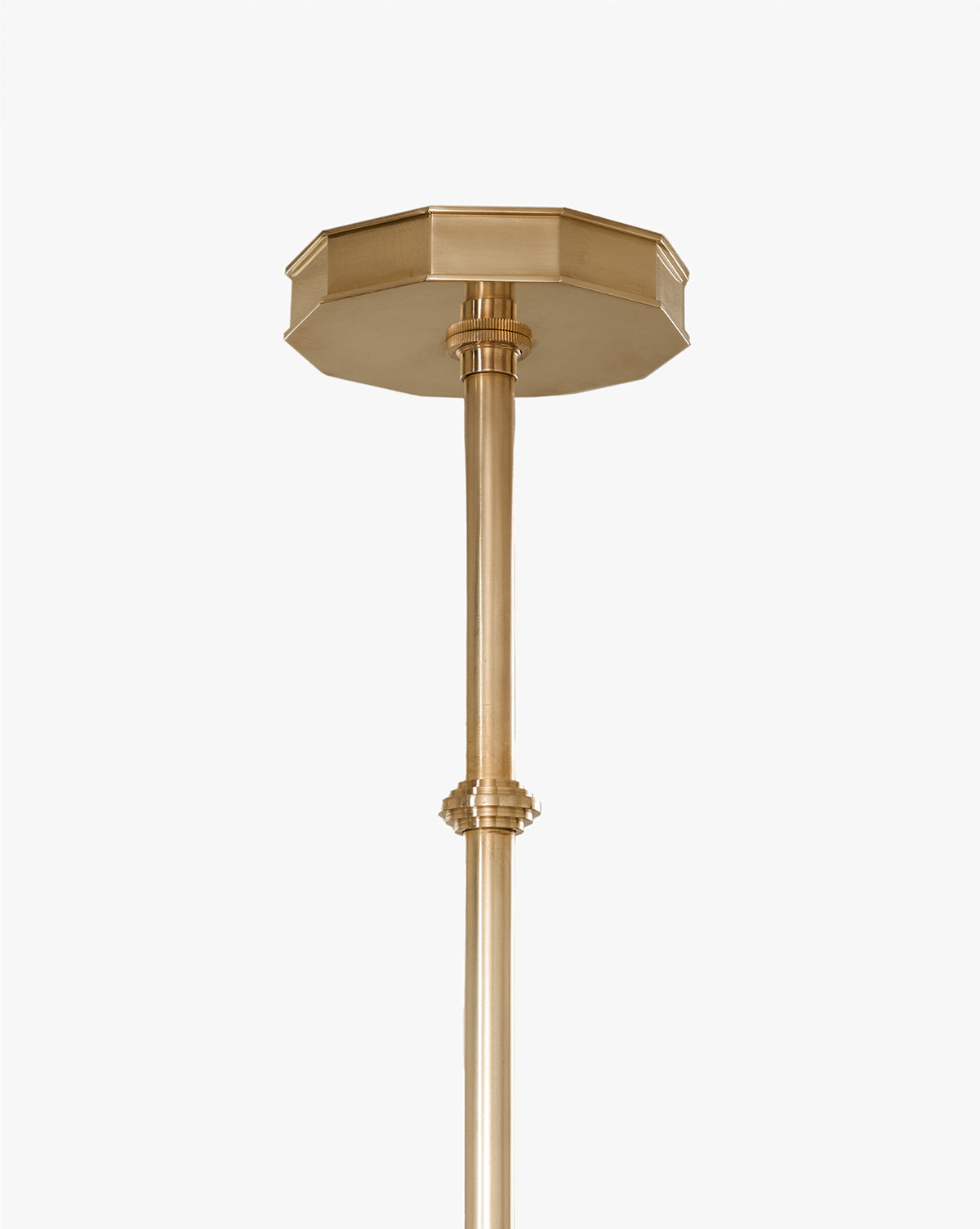 A close-up of the Knightley Chandelier shows its brass ceiling mount with a decorative octagonal canopy and straight rod, evoking an antique look, set against a plain white background, by McGee & Co.