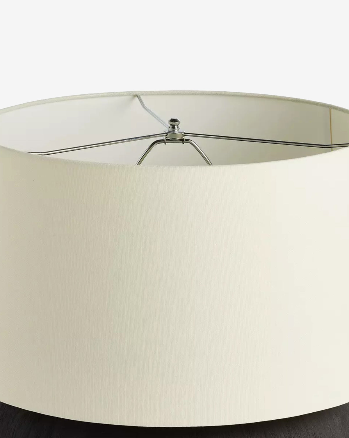 A close-up of the Kragen Table Lamp with a round ivory linen shade and visible metal framing, placed on a dark surface against a white background, by McGee & Co.