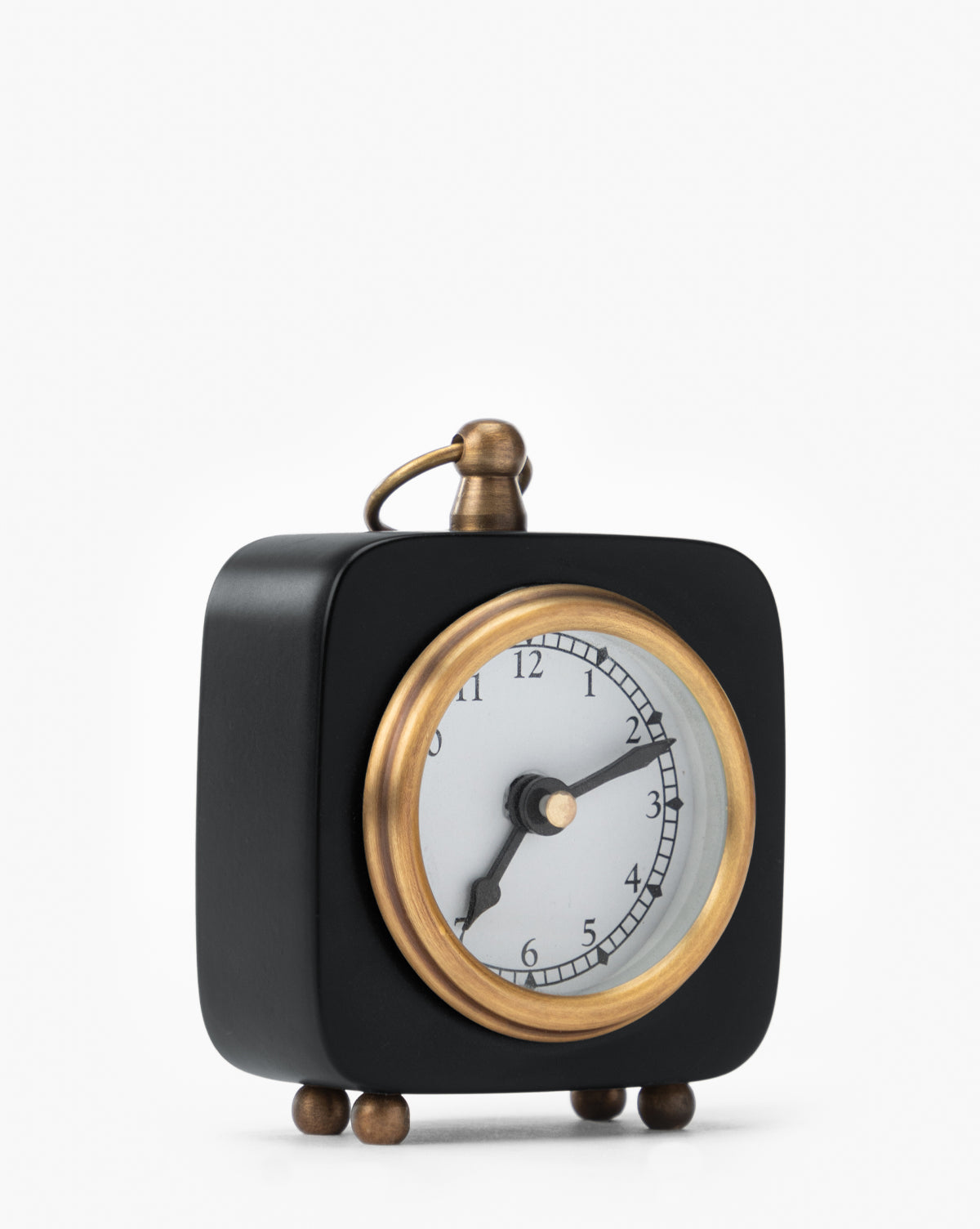The Kya Clock is a small, black, square accent clock with a gold frame and feet. Its simple face shows 8:00 with black hands, making it perfect for adding style to your nightstand. The background is plain white, by McGee & Co.