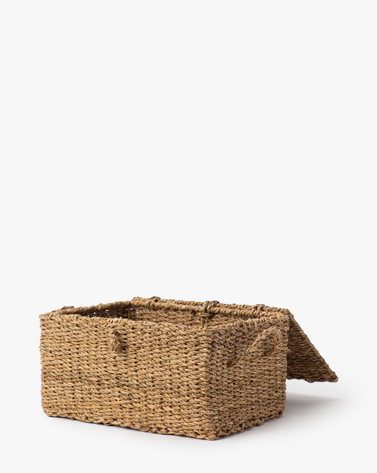 The Kya Seagrass Box, a rectangular hand-woven basket with a hinged lid made from natural fibers, is shown partially open on a plain white background by McGee & Co.