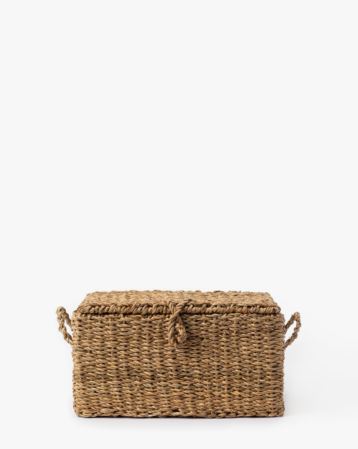 The Kya Seagrass Box is a rectangular, hand-woven basket with a lid and two side handles, crafted from natural fibers—an ideal decorative storage piece for your home, by McGee & Co.