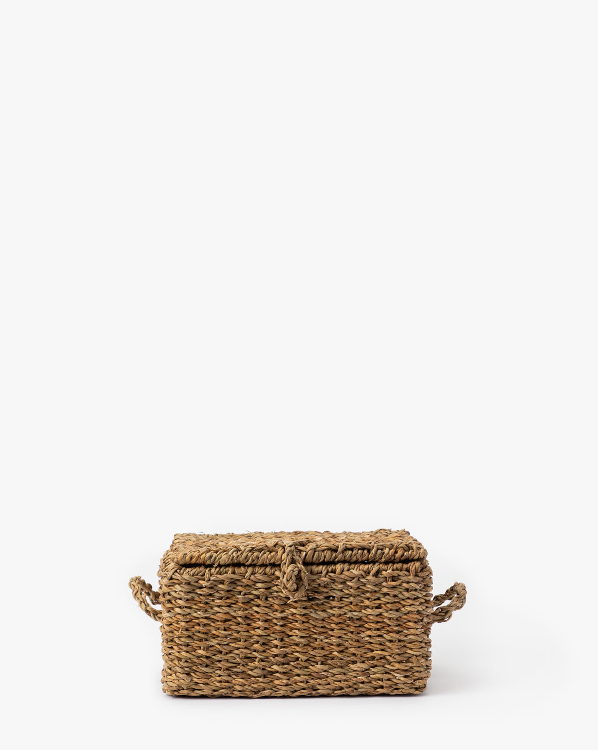 The Kya Seagrass Box is a rectangular, hand-woven basket with a lid and side handles, crafted from natural fibers and shown on a white background—ideal for anyone seeking stylish or decorative seagrass storage by McGee & Co.