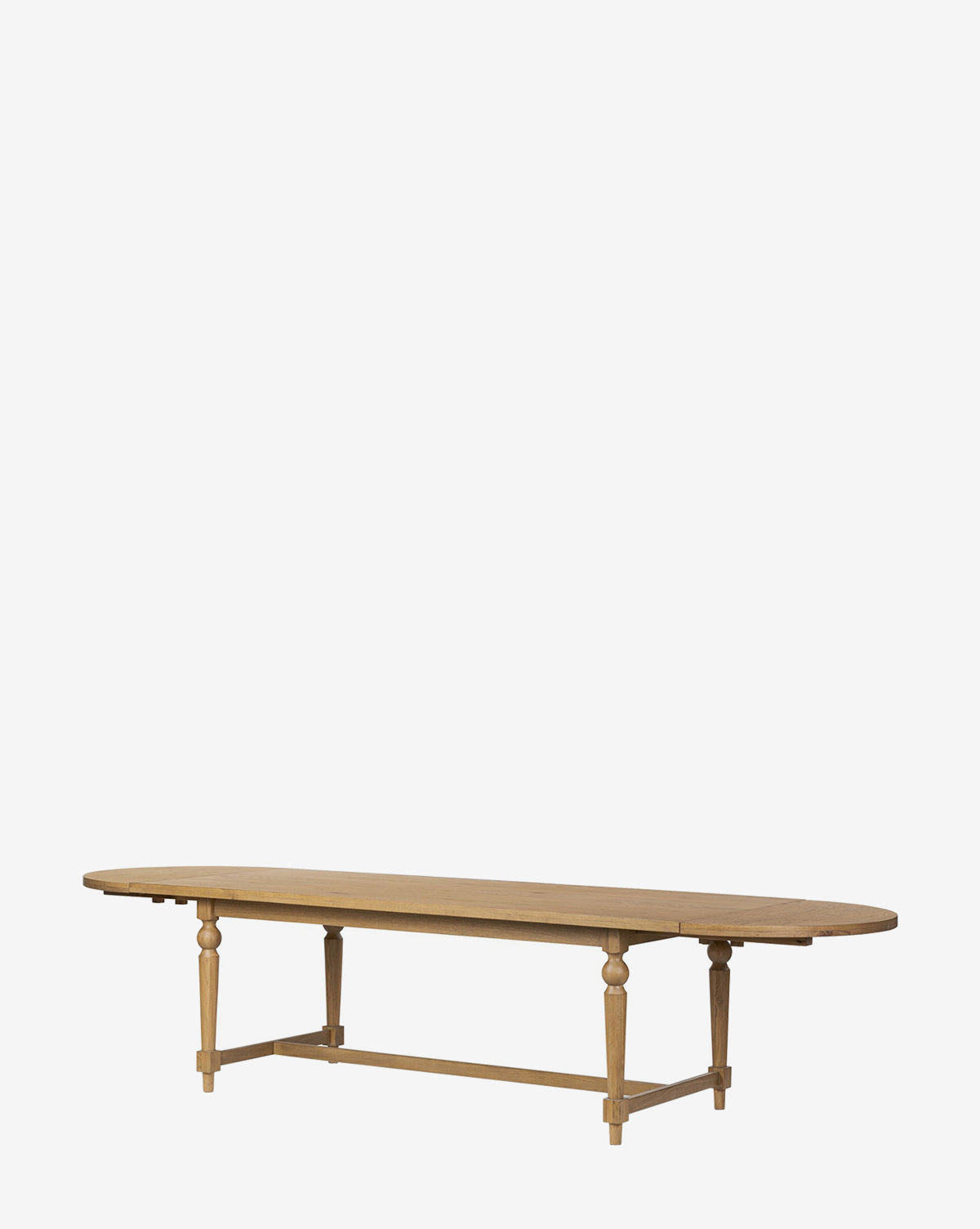 The Kyler Oak Extension Dining Table features a long, oval top, four turned legs, and a rectangular base support. Its natural wood finish highlights clean Scandinavian lines, shown here against a plain white background by McGee & Co.