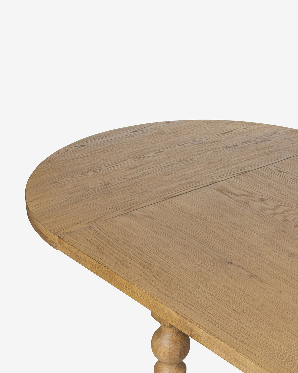 A close-up of the Kyler Oak Extension Dining Table highlights its light brown finish, rounded edge, smooth wood grain, and the visible seam on its extendable oval surface, by McGee & Co.