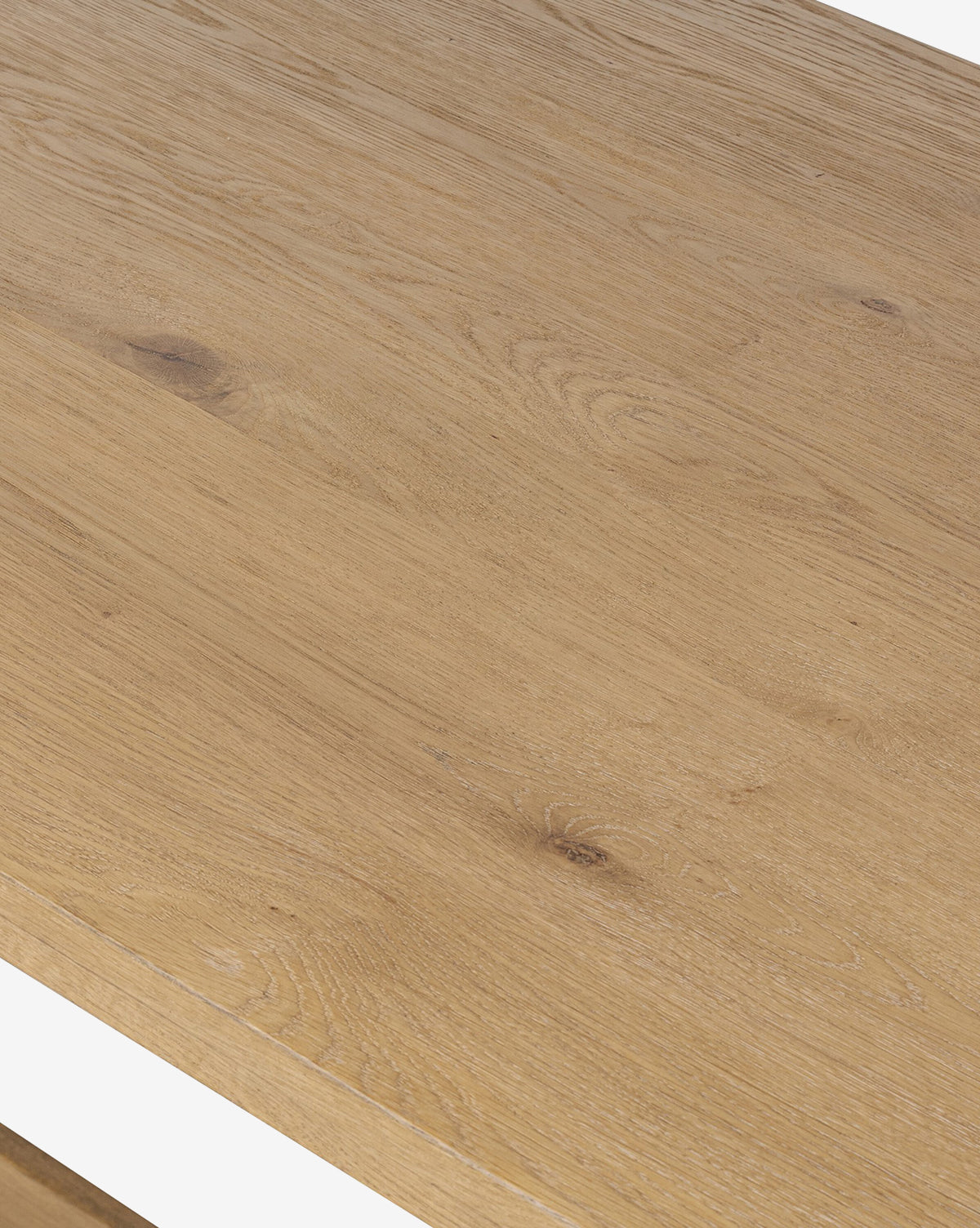 A close-up of the Kyler Oak Extension Dining Table showcases its natural light brown oak surface, featuring visible wood grain and knots that highlight its unique Scandinavian modern texture and pattern, by McGee & Co.