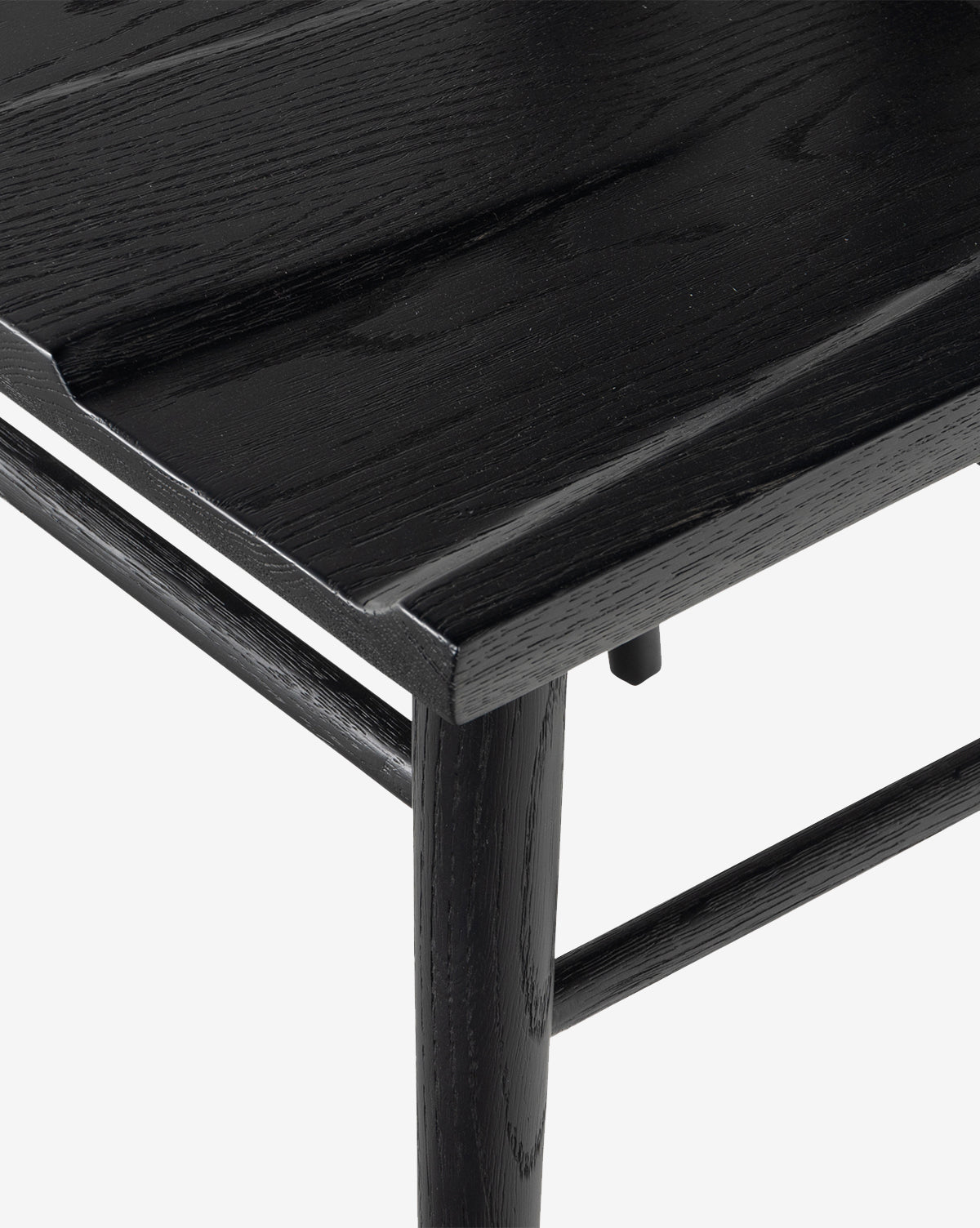 Close-up of the Lahargoue Dining Chair corner, showing its black oak finish, smooth surface, visible wood grain, and part of the leg and frame against a white background by McGee & Co.