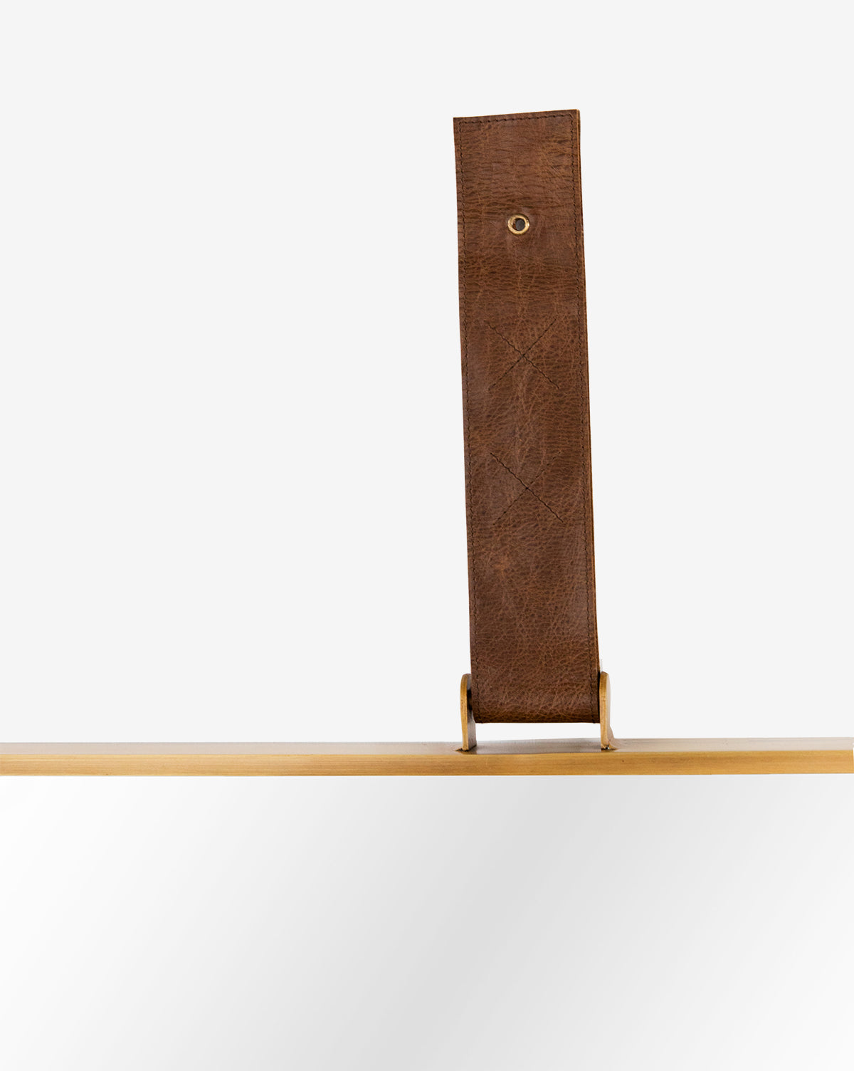 A close-up of the Laila Rectangle Mirror featuring a tan wooden frame and wide leather hanger with brass hardware, suspended against a plain white background, by McGee & Co.