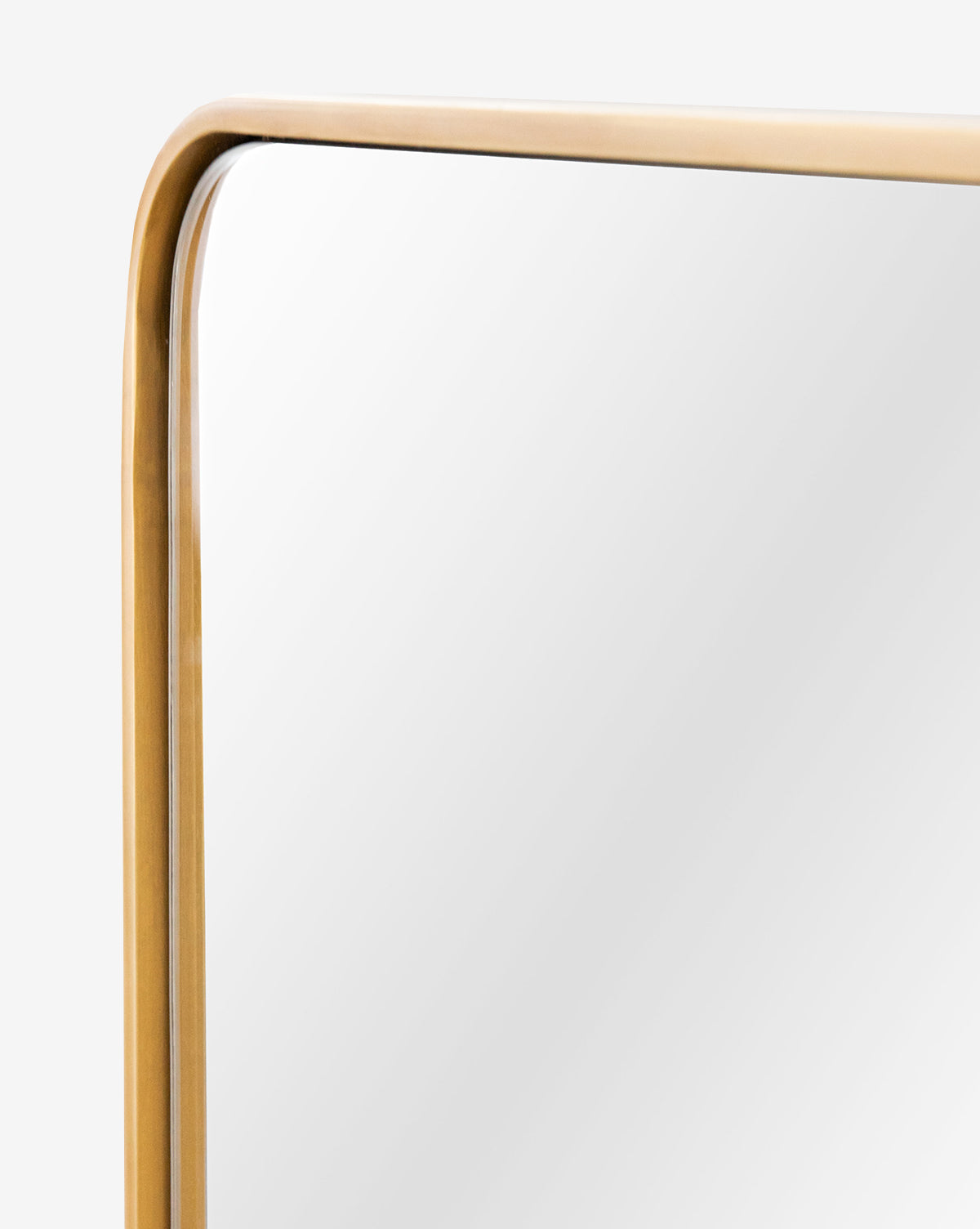A close-up of the Laila Rectangle Mirrors top corner shows its rounded edge and gold metal frame with elegant brass hardware, set against a plain light background, by McGee & Co.
