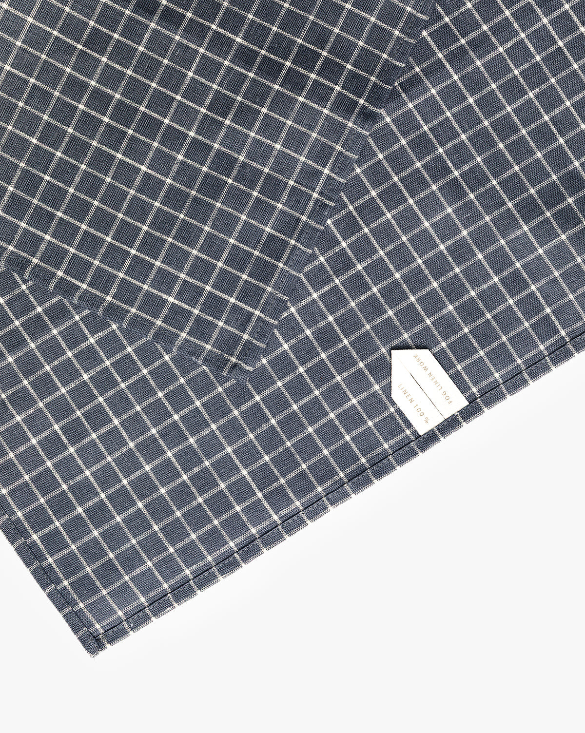 A close-up of the Lancaster Linen Tea Towel, neatly folded in a navy and white check pattern with a white label in the bottom right corner—a timeless kitchen essential, by McGee & Co.