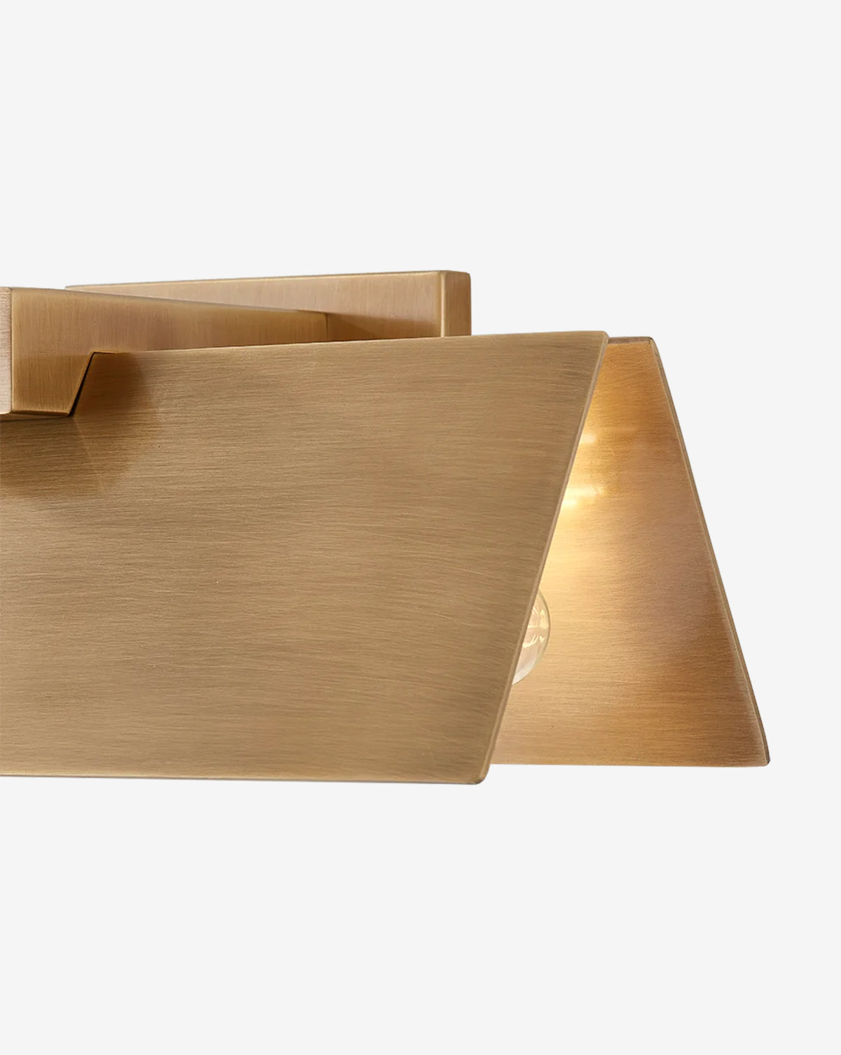 Close-up of the Lander Wall Sconce, a contemporary fixture in patina brass with a brushed finish, showcasing a softly glowing bulb behind its geometric metal shade, by McGee & Co.