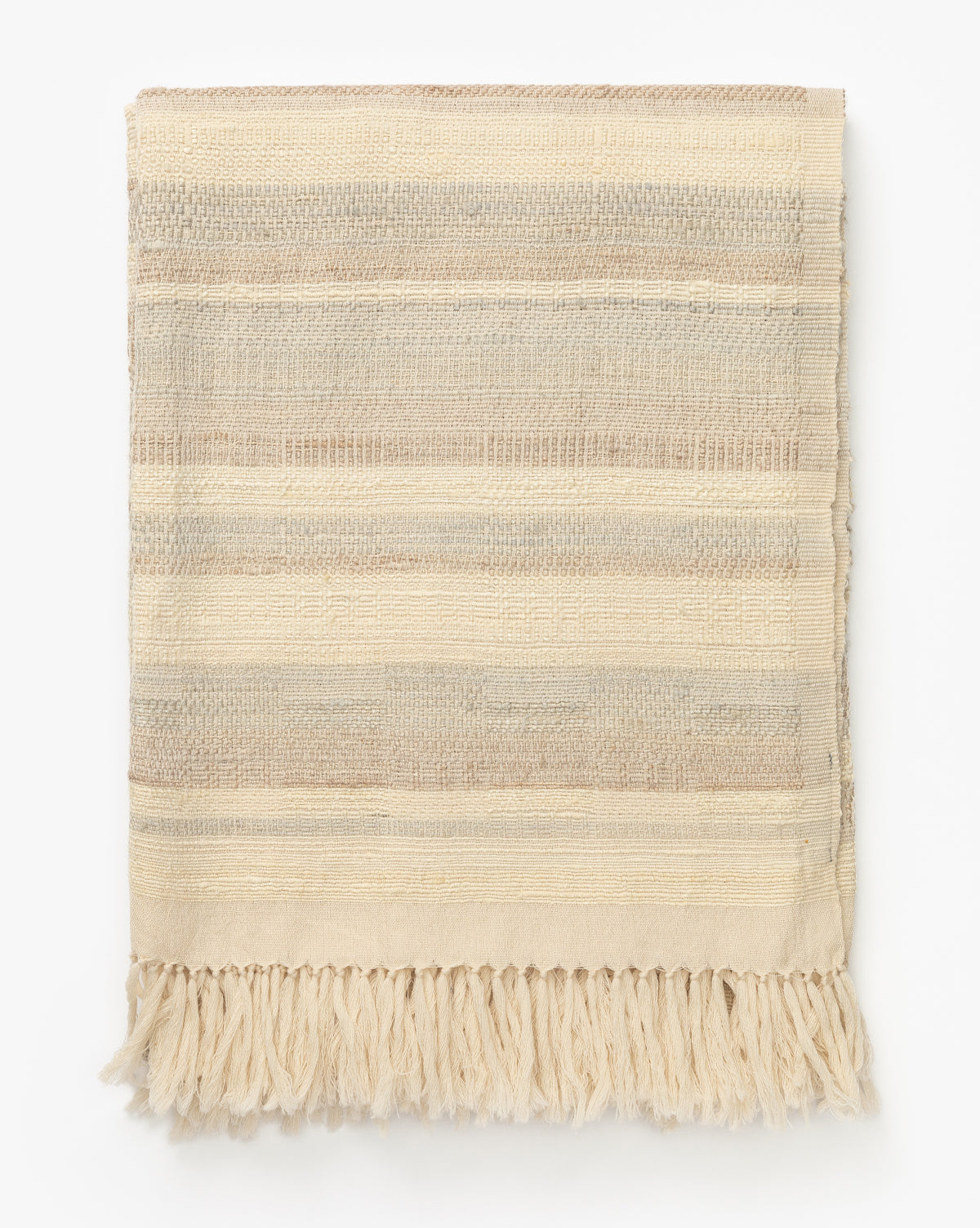 The Laney Stripe Throw by TAL HANDWOVEN CLASSICS LLP is a folded wool and silk blanket with beige, cream, and light brown horizontal stripes and fringe tassels along the bottom edge, displayed on a white background, McGee & Co.