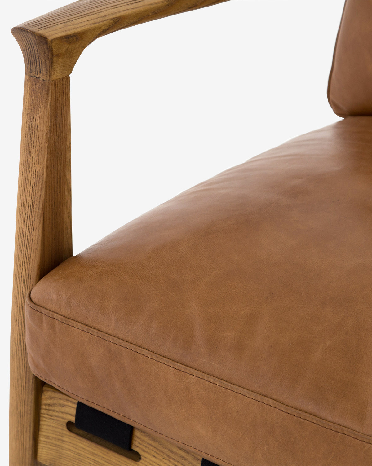 Close-up of the Lanston Lounge Chair with an ash wood frame and tan leather cushions, focusing on the armrest, seat, and backrest details against a light background, by McGee & Co.