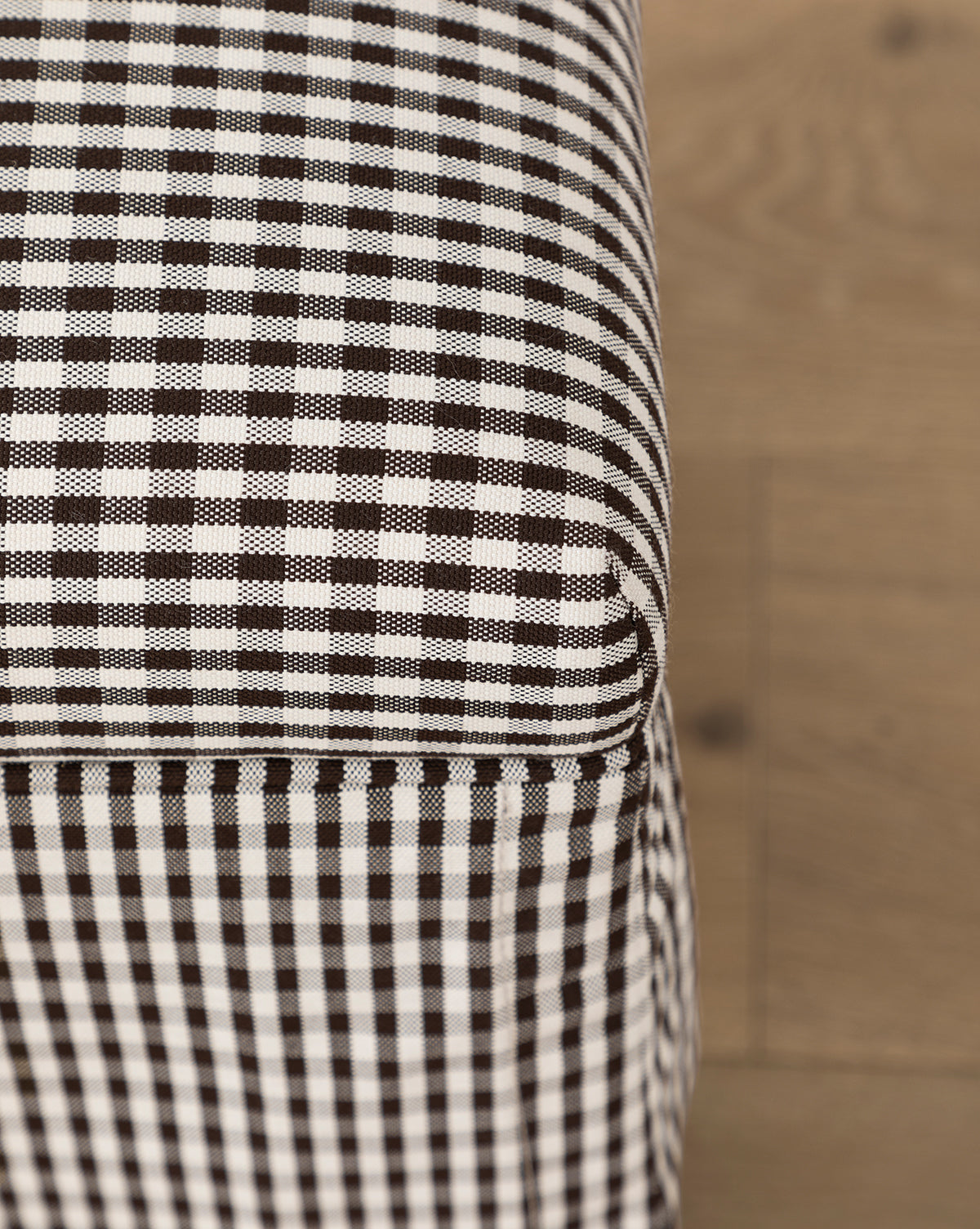 Certainly! Here’s a blended product description with the exact string McGee & Co. at the end: Close-up of the Latimer Ottoman (Ready to Ship) by Makerspalm, a functional accent piece in high-quality black and white checkered fabric, shown on a wooden floor. McGee & Co.