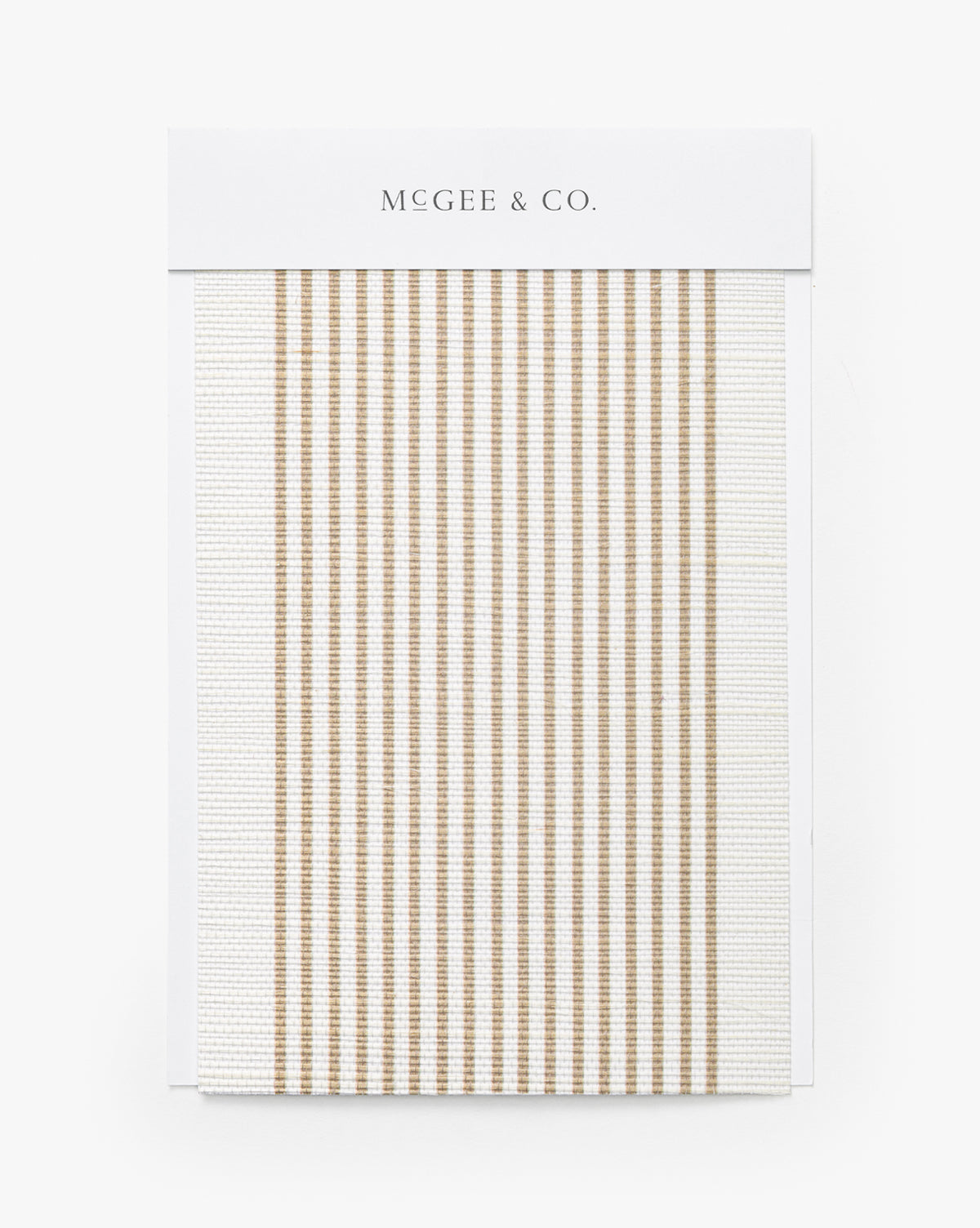 A Leah Striped Sisal Wallpaper Swatch by York Wallcoverings features thin, vertical beige stripes on a white background, resembling modern stripe wallpaper, displayed on a branded card by McGee & Co.