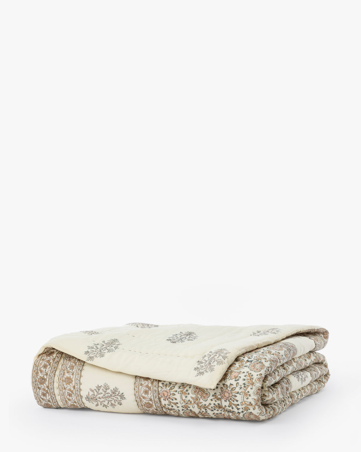 The Leander Quilt is a folded, cream-colored cotton quilt featuring a subtle floral and intricate border pattern in light brown tones—ideal for adding timeless elegance to your bedding.