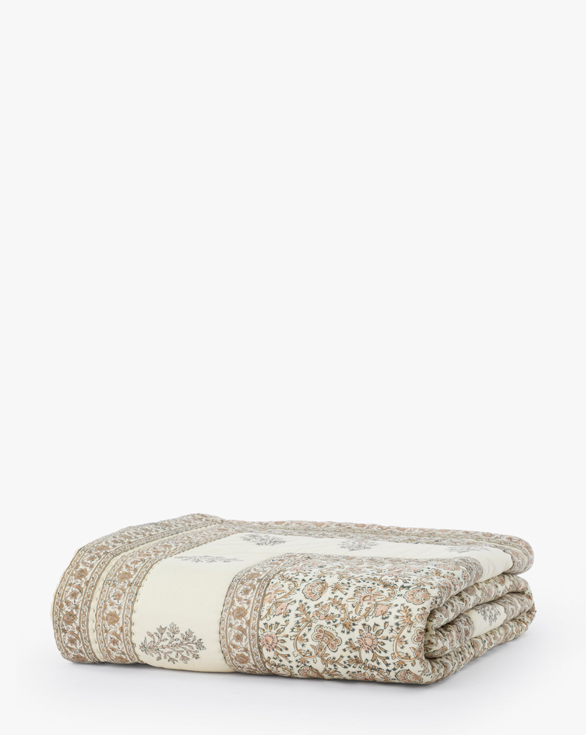 The Leander Quilt is a folded, cream-colored cotton quilt featuring intricate brown floral block prints and decorative borders—an elegant addition to your bedding, beautifully displayed on a white background.