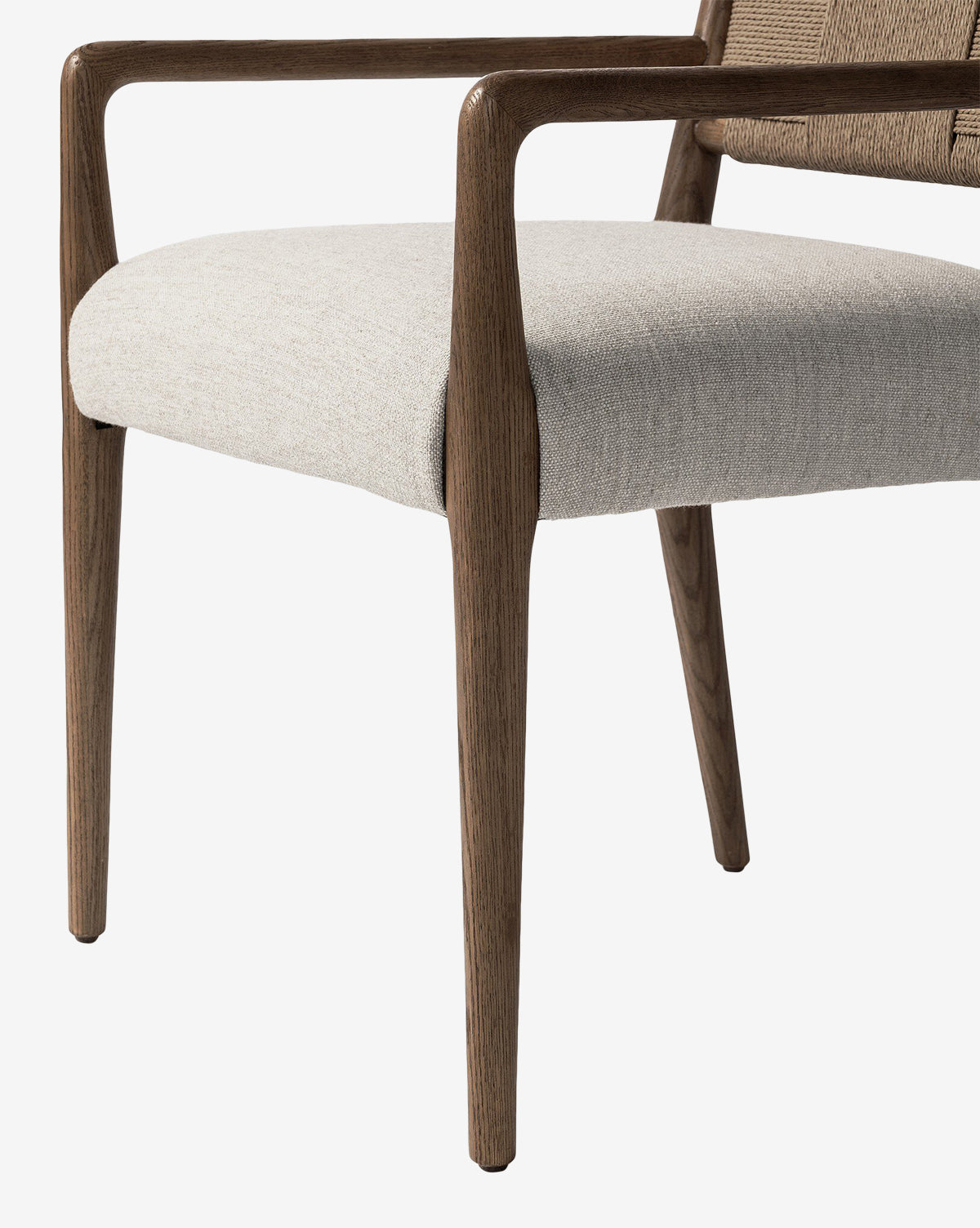 A close-up of the Leola Dining Armchair features wooden legs and armrests, plus a light beige upholstered seat, all set against a white background by McGee & Co.