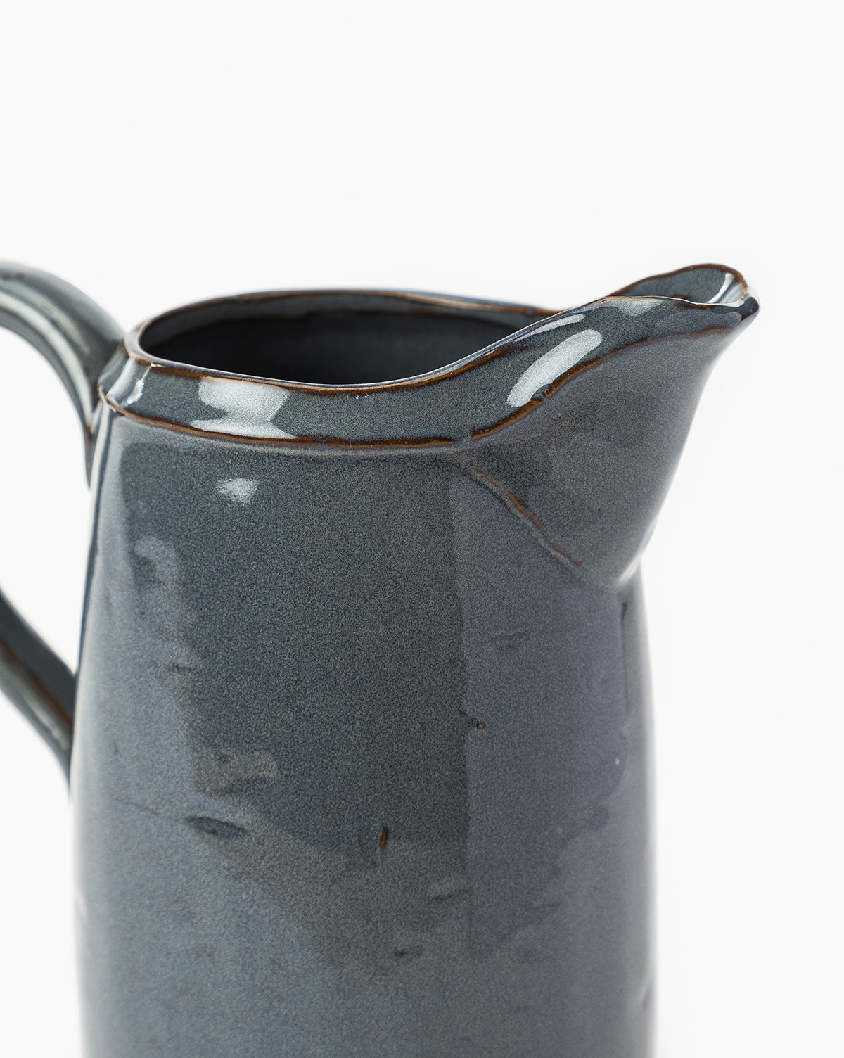 A close-up of the Levine Ceramic Pitcher in deep blue with a glossy dark gray glaze, highlighting its handle and spout against a white background—ideal for modern kitchen decor, by McGee & Co.