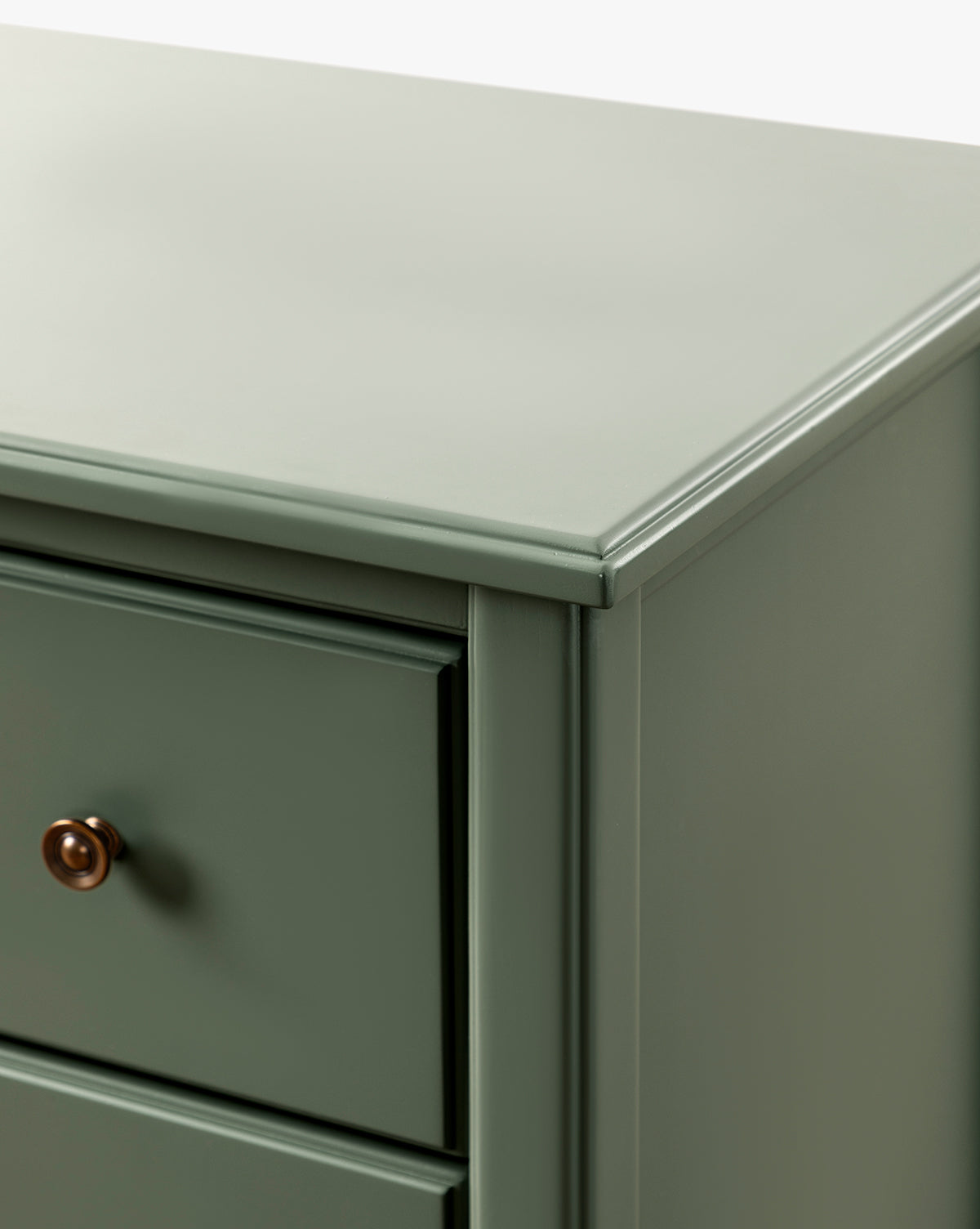 Close-up of the top corner and side of the Liberty 6-Drawer Assembled Dresser, crafted from sustainable pine wood with a smooth green finish, showing part of a drawer and its round, dark-colored knob, by McGee & Co.