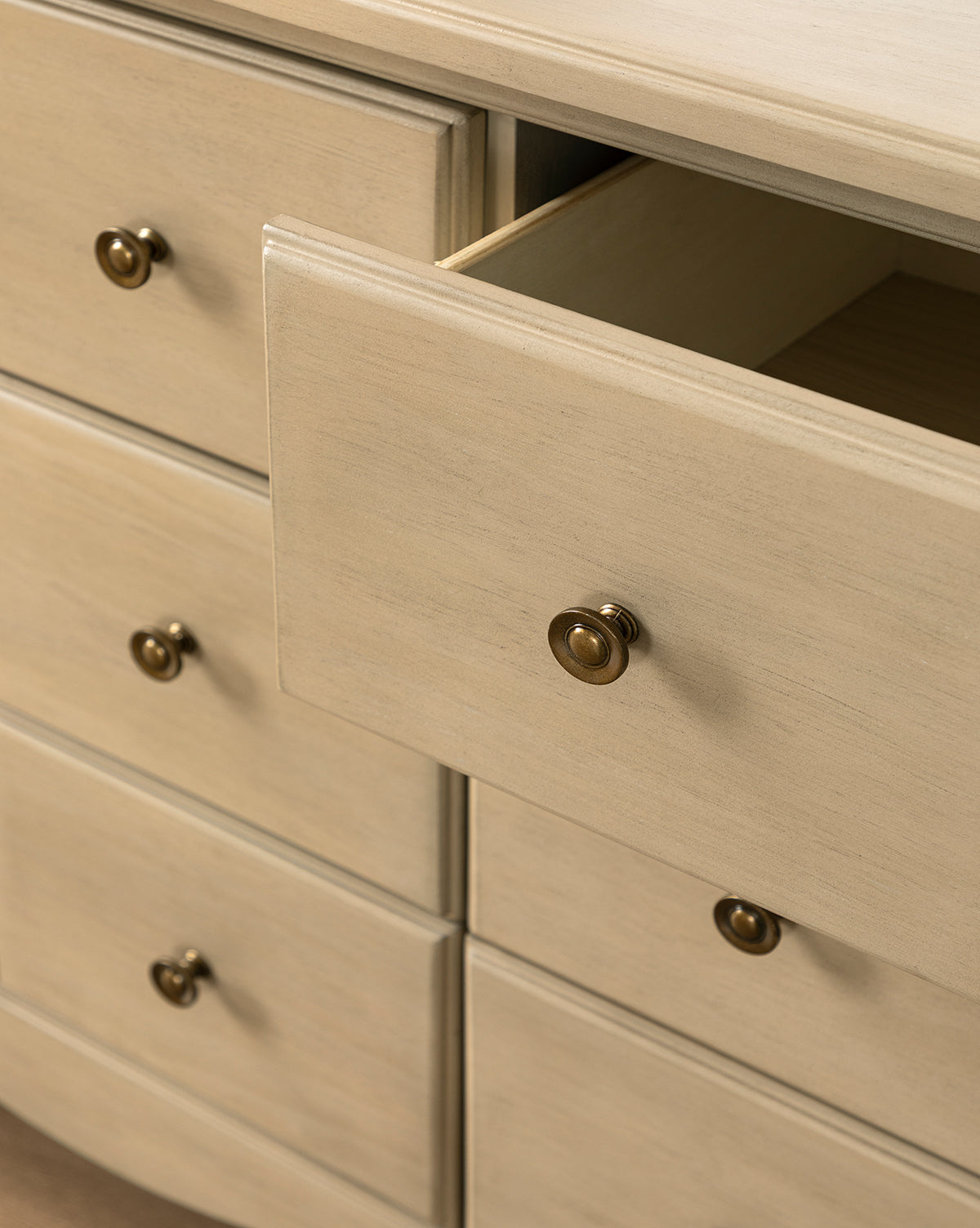 Close-up of the Liberty 6-Drawer Assembled Dresser, made from sustainable pine wood with round brass knobs. One spacious drawer is slightly open, showing an empty interior. The dresser features a smooth finish and multiple roomy drawers by McGee & Co.