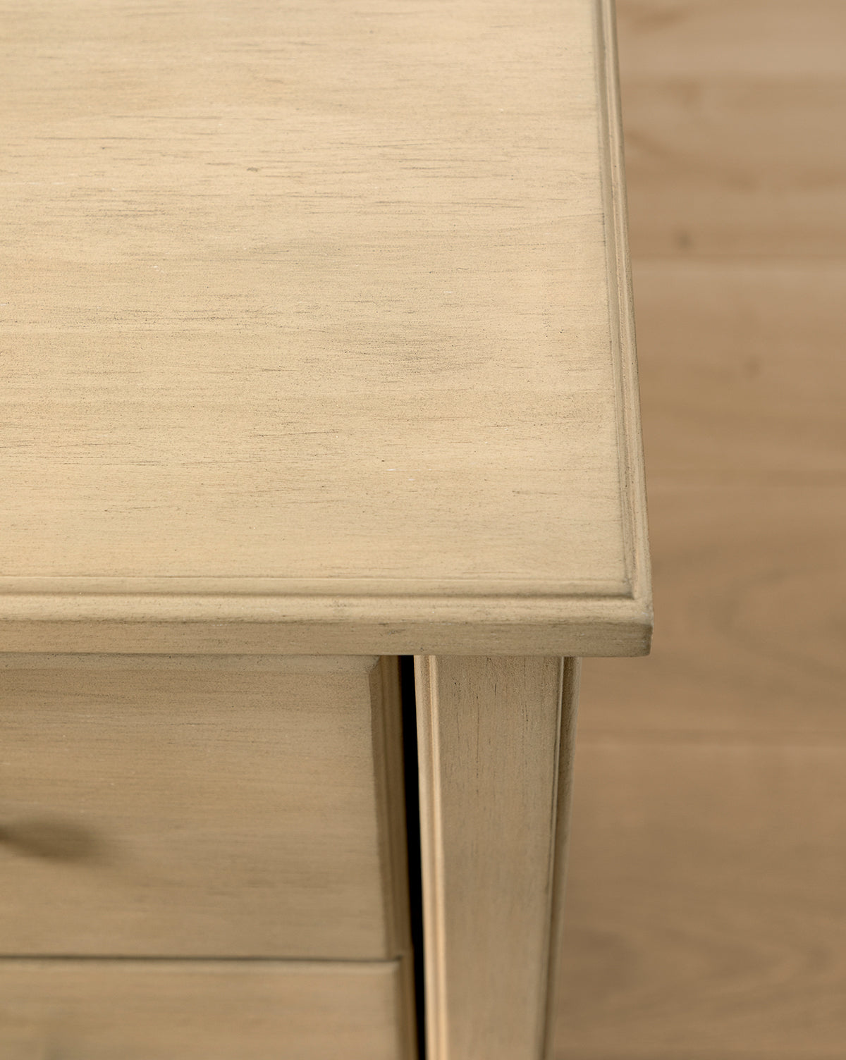 Close-up of the top corner and side of the Liberty 6-Drawer Assembled Dresser, showcasing its sustainable pine wood construction, visible grain, smooth finish, a partially open drawer below, and wood flooring in the background, by McGee & Co.