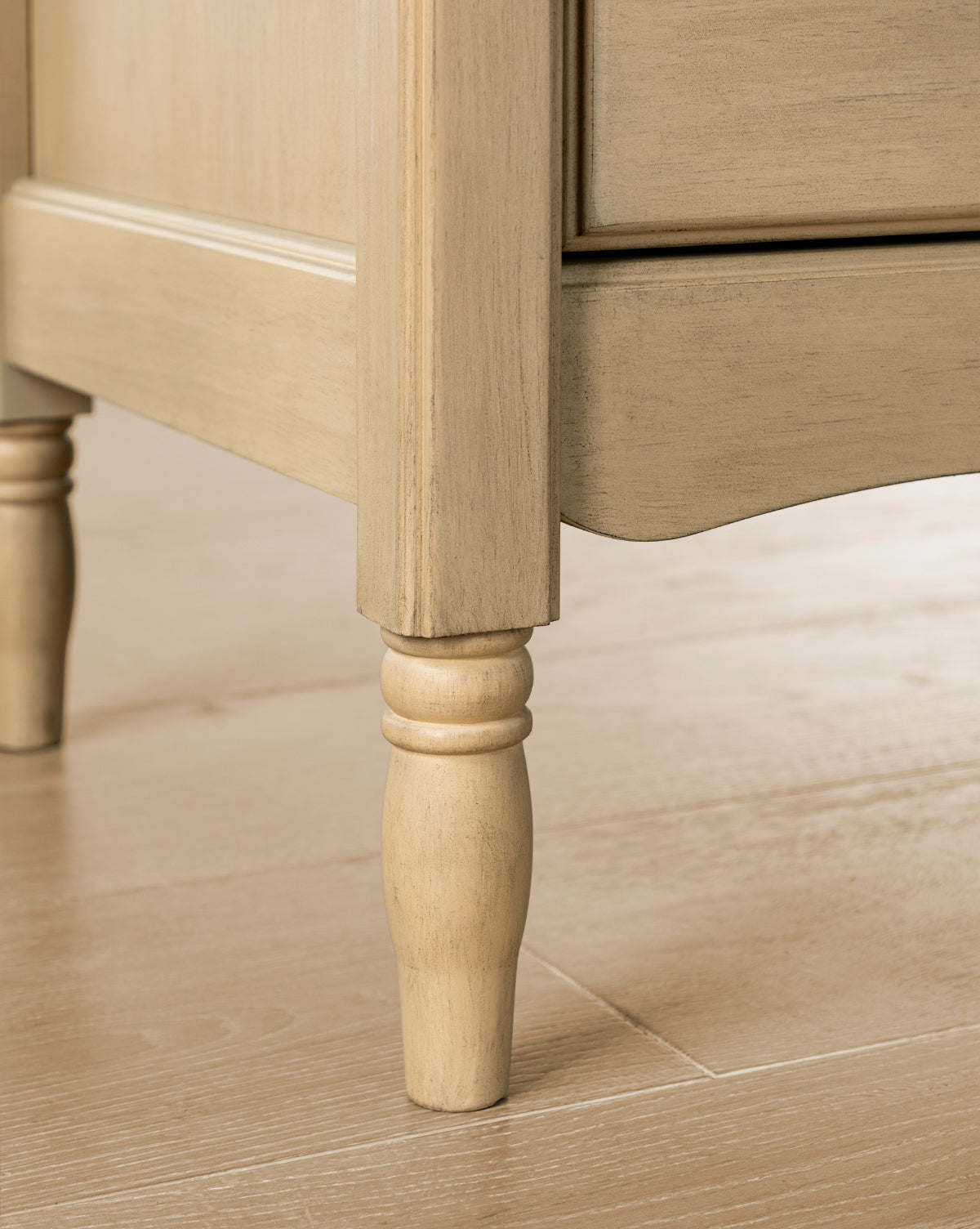 Close-up of the Liberty 6-Drawer Assembled Dresser, crafted from sustainable pine wood with a decorative turned leg and paneled side, shown on a light wood floor by McGee & Co.
