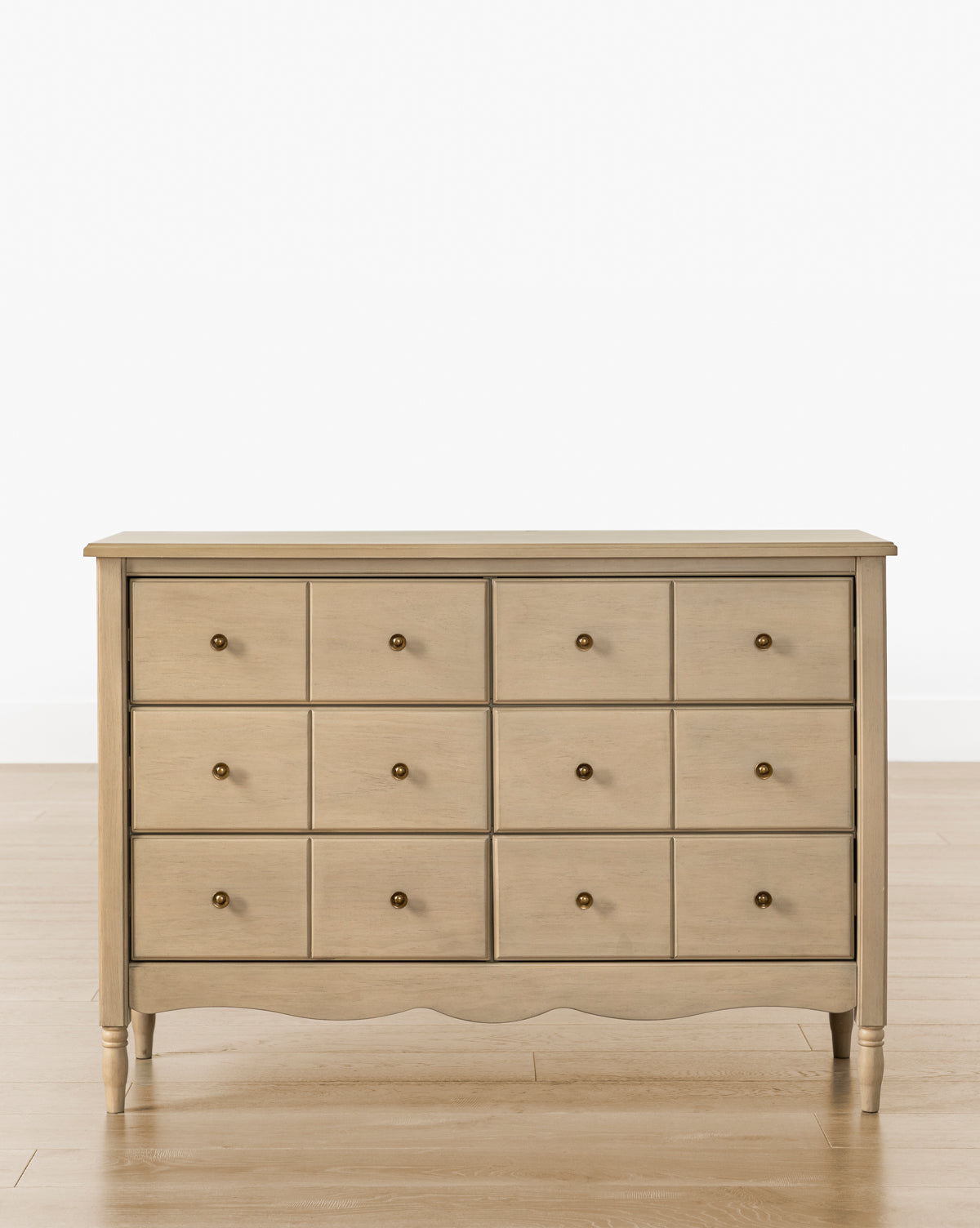 The Liberty 6-Drawer Assembled Dresser, made from sustainable pine, features six drawers with round metal knobs and stands on four short legs on a wooden floor against a plain white background, by McGee & Co.