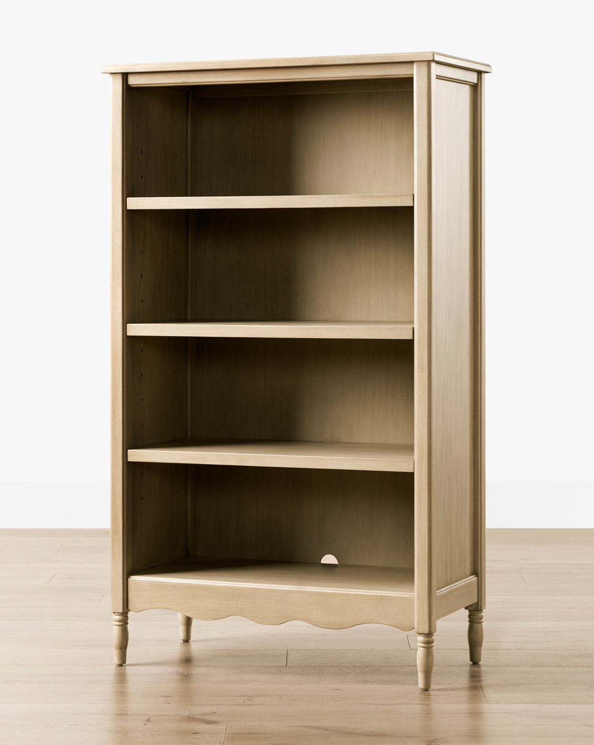 The Liberty Bookcase features a light wood finish, three shelves, and a scalloped base. Its classic design with turned legs adds timeless elegance, making it a stylish addition to any room, by McGee & Co.