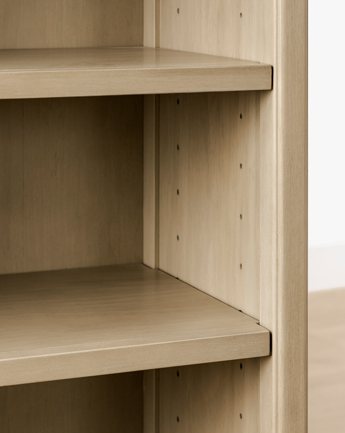 Close-up of the Liberty Bookcase, an empty wooden bookshelf with adjustable shelves, heirloom craftsmanship, light wood finish, and visible peg holes on the side panels by McGee & Co.