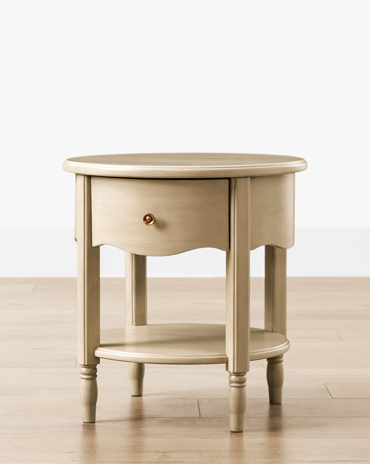 The Liberty Nightstand features a round, light wood design with a single drawer, lower shelf, four turned legs, and a small round knob—perfect for nurseries and GREENGUARD Gold Certified for healthier indoor air, by McGee & Co.