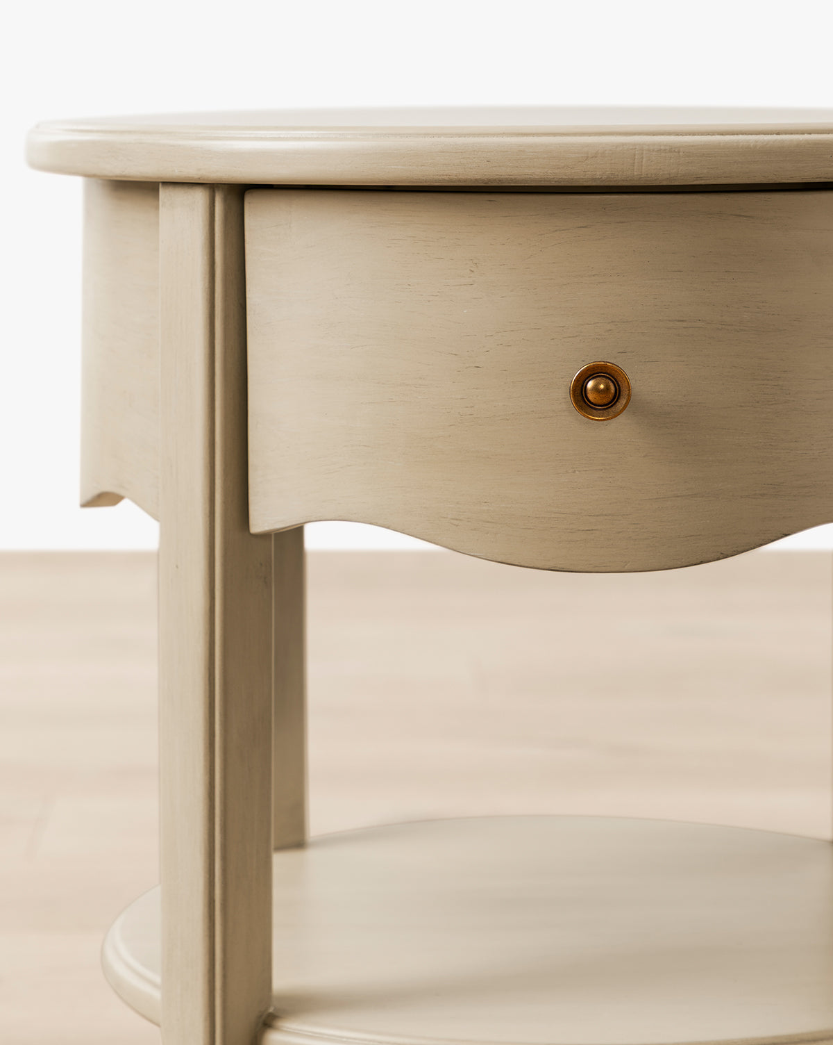 The Liberty Nightstand is a round wooden table with a curved-front drawer and lower shelf in light beige—ideal for nurseries and GREENGUARD Gold Certified for cleaner indoor air, by McGee & Co.