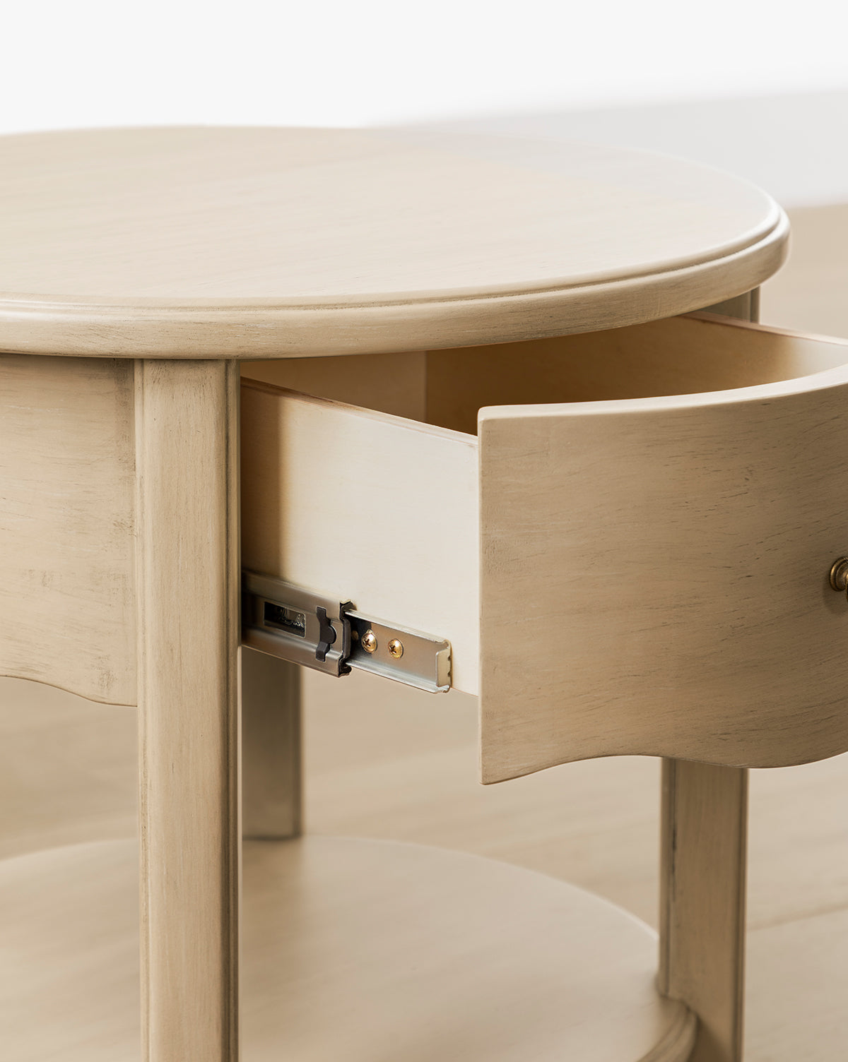 The Liberty Nightstand is a round wooden nightstand with a natural finish, featuring a curved drawer and metal sliding mechanism, offering both style and function as a nursery nightstand, by McGee & Co.