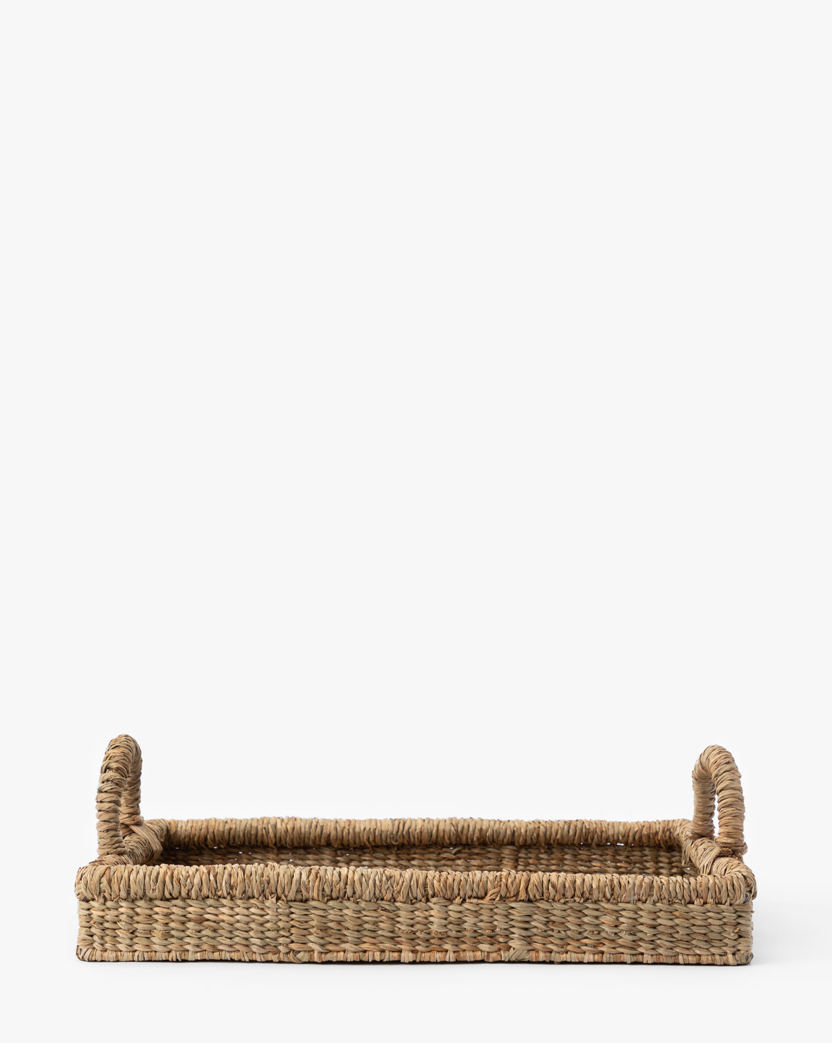 The Liesl Tray is a rectangular woven mendong grass tray with raised edges and two upright handles on each short side, crafted from natural fibers—ideal as organic home decor or a decorative tray, shown against a plain white background.