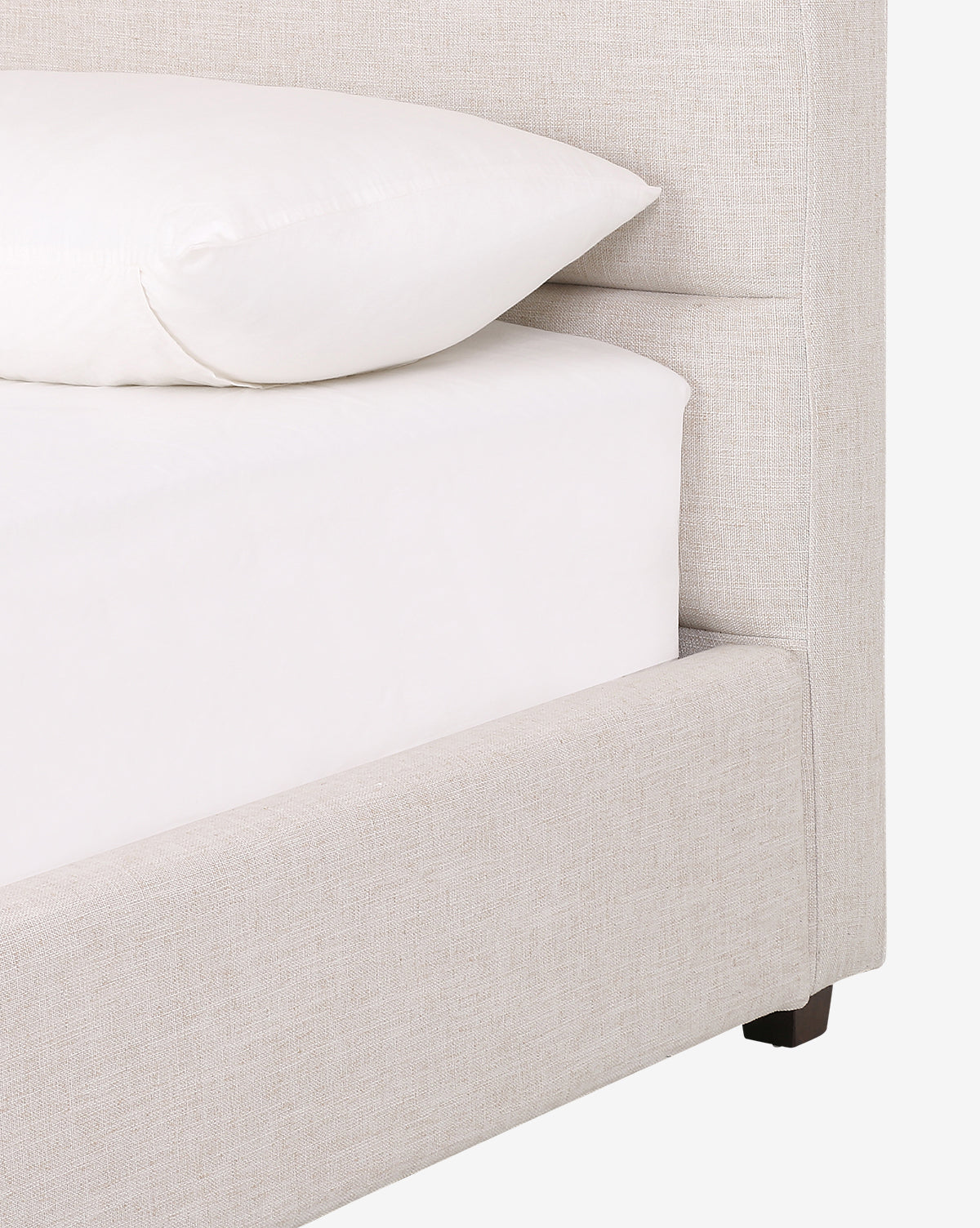 Close-up of the Lila Bed in beige upholstery with a white fitted sheet and pillow, showcasing its textured fabric and modern silhouette for a sleek, contemporary style.