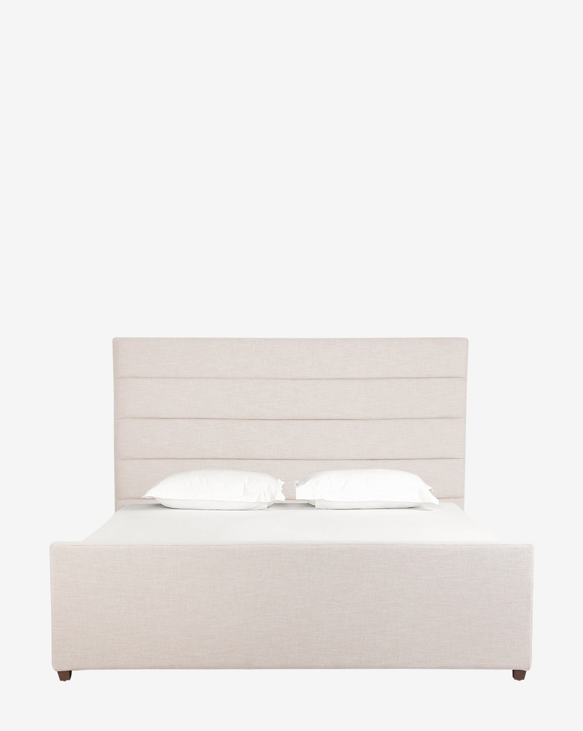 The Lila Bed showcases a modern silhouette with a tall, horizontal-panel headboard and beige upholstery, complemented by a white fitted sheet and two white pillows, set against a plain white background.